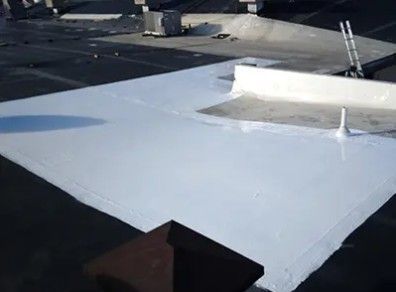 White coating applied to a flat black roof, possibly for waterproofing or energy efficiency. A white parapet wall is visible.