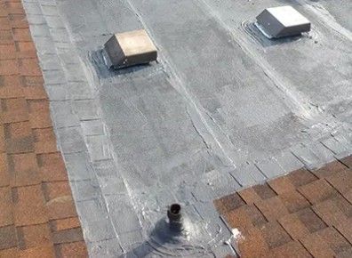 Roof with shingles and flat section sealed with a gray sealant, with three vents.