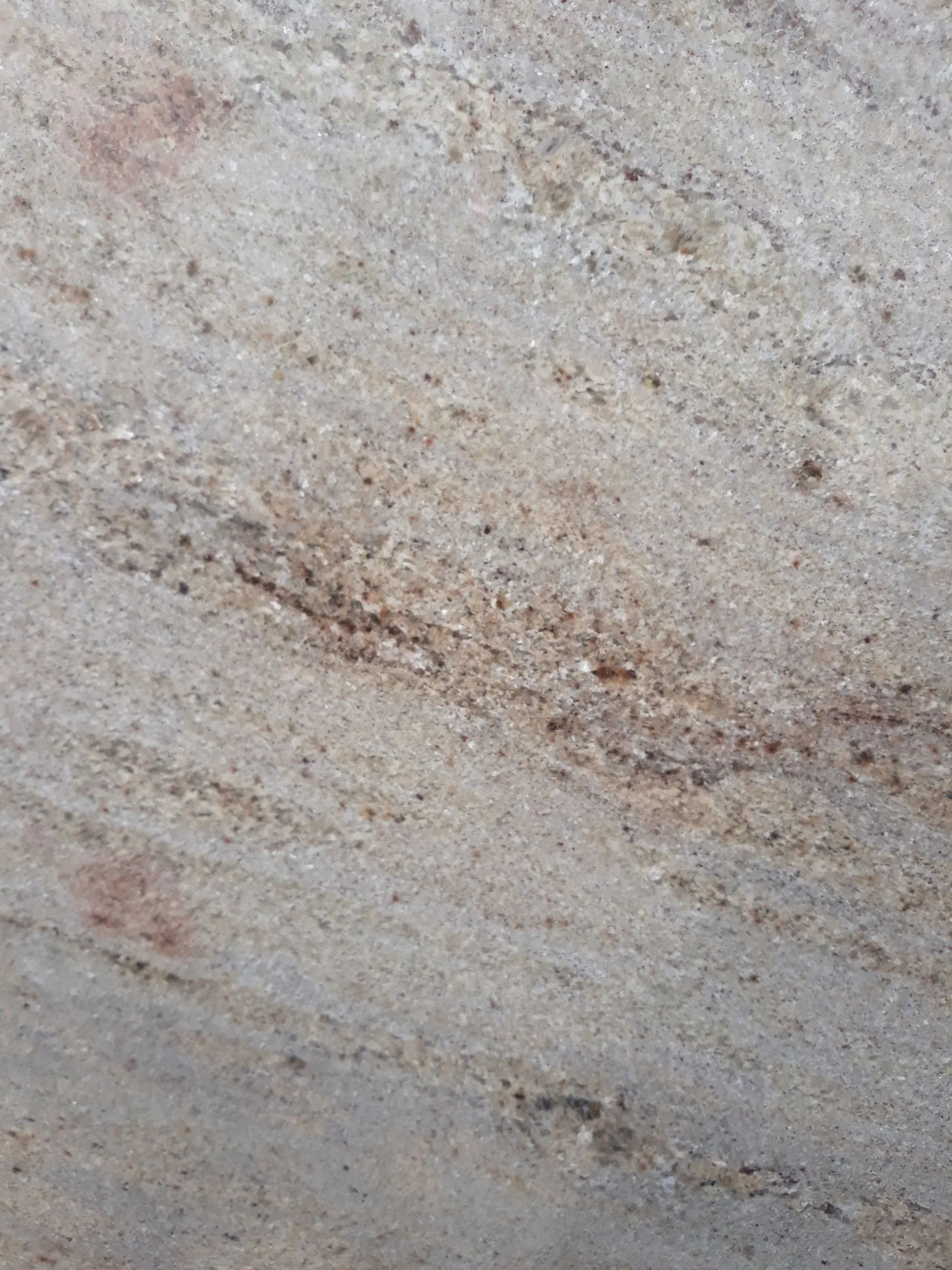 Close-up of a beige, speckled stone or tile surface with faint brown and gray streaks