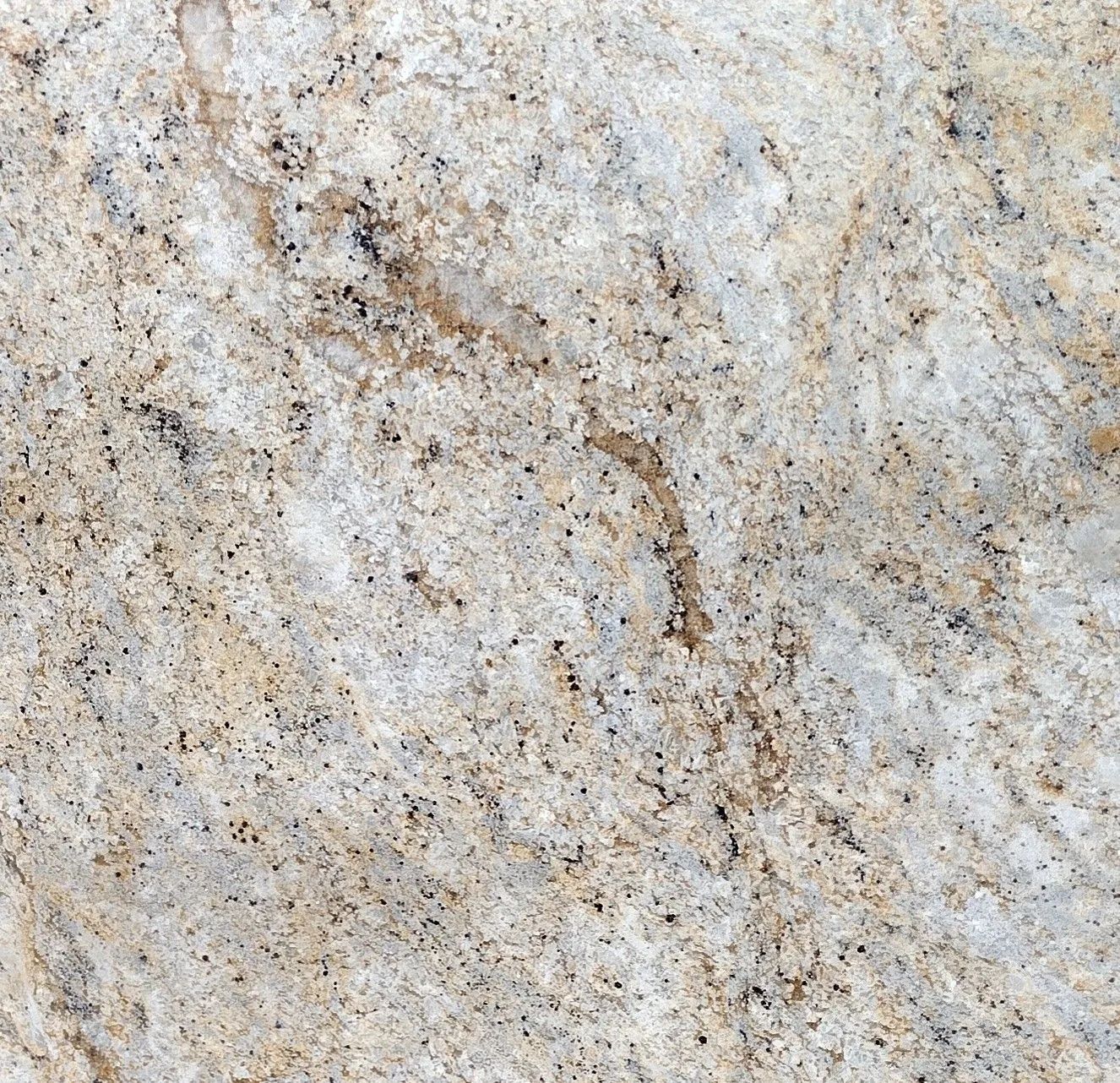 Close-up of a beige and gray speckled stone surface with brown veining