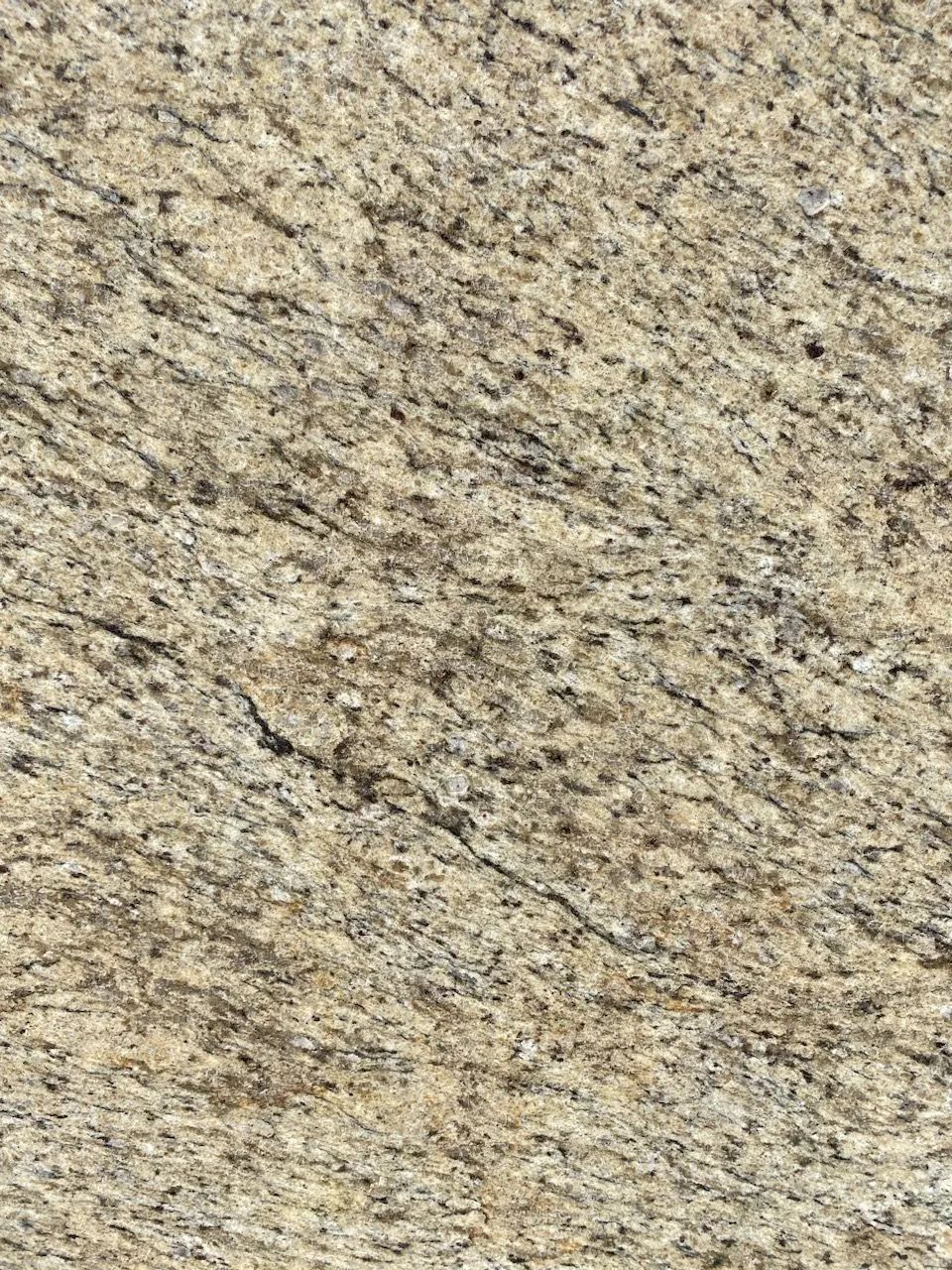 Close-up of beige speckled stone surface with fine gray and black flecks