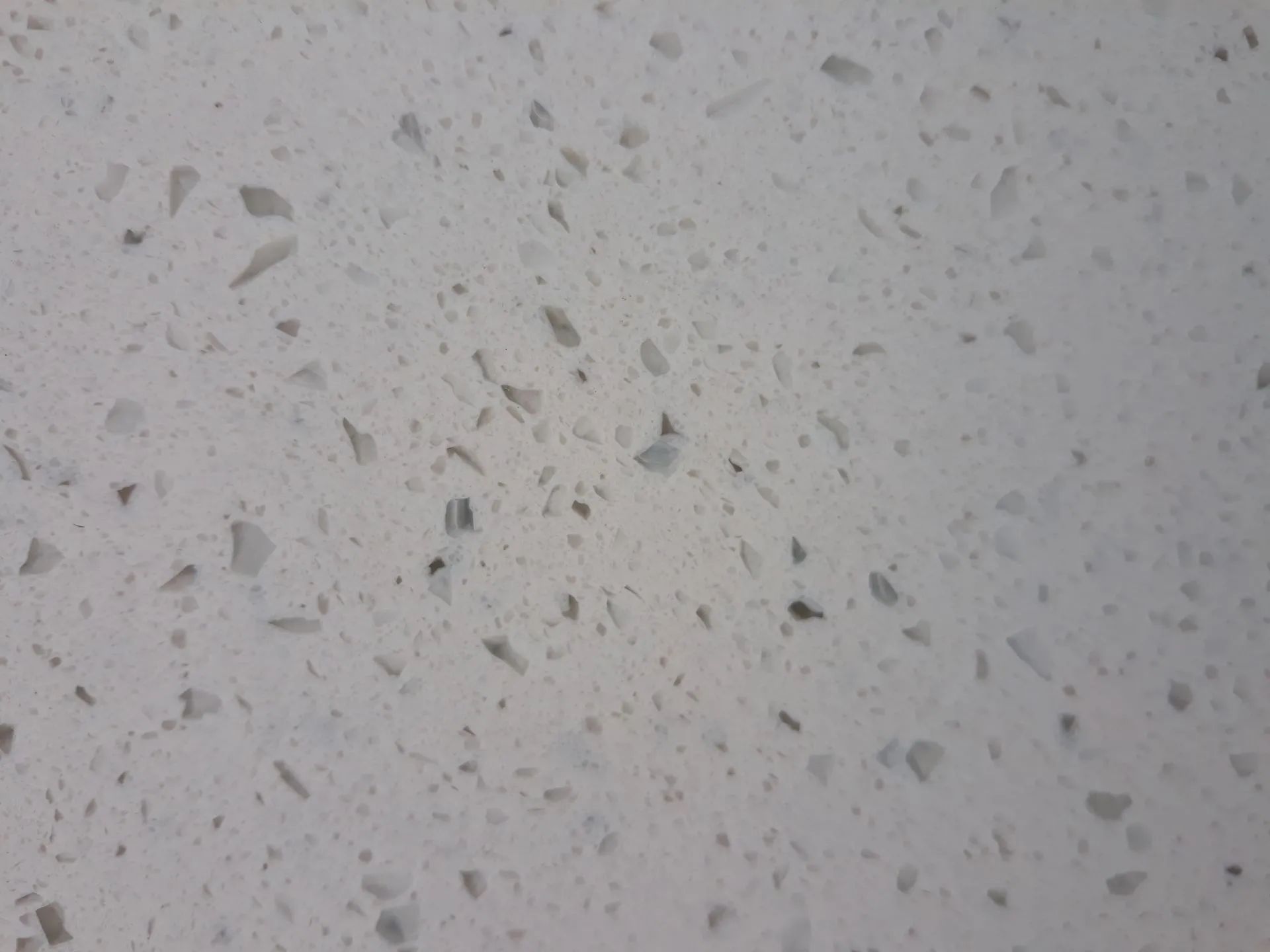 Light gray speckled terrazzo surface with scattered dark flecks