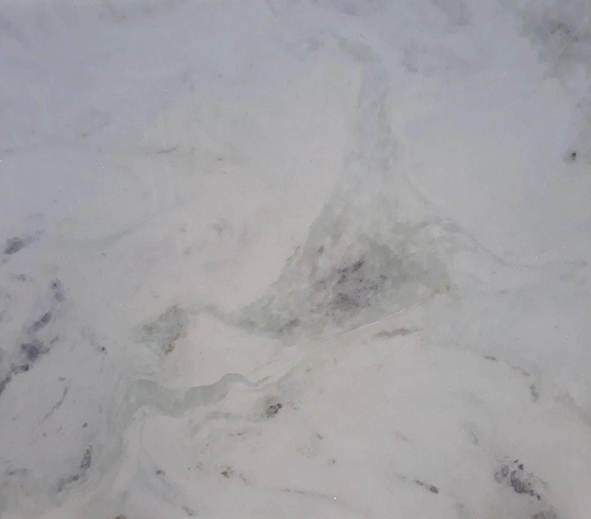 White marble-like stone surface with subtle gray veining and cloudy patterns