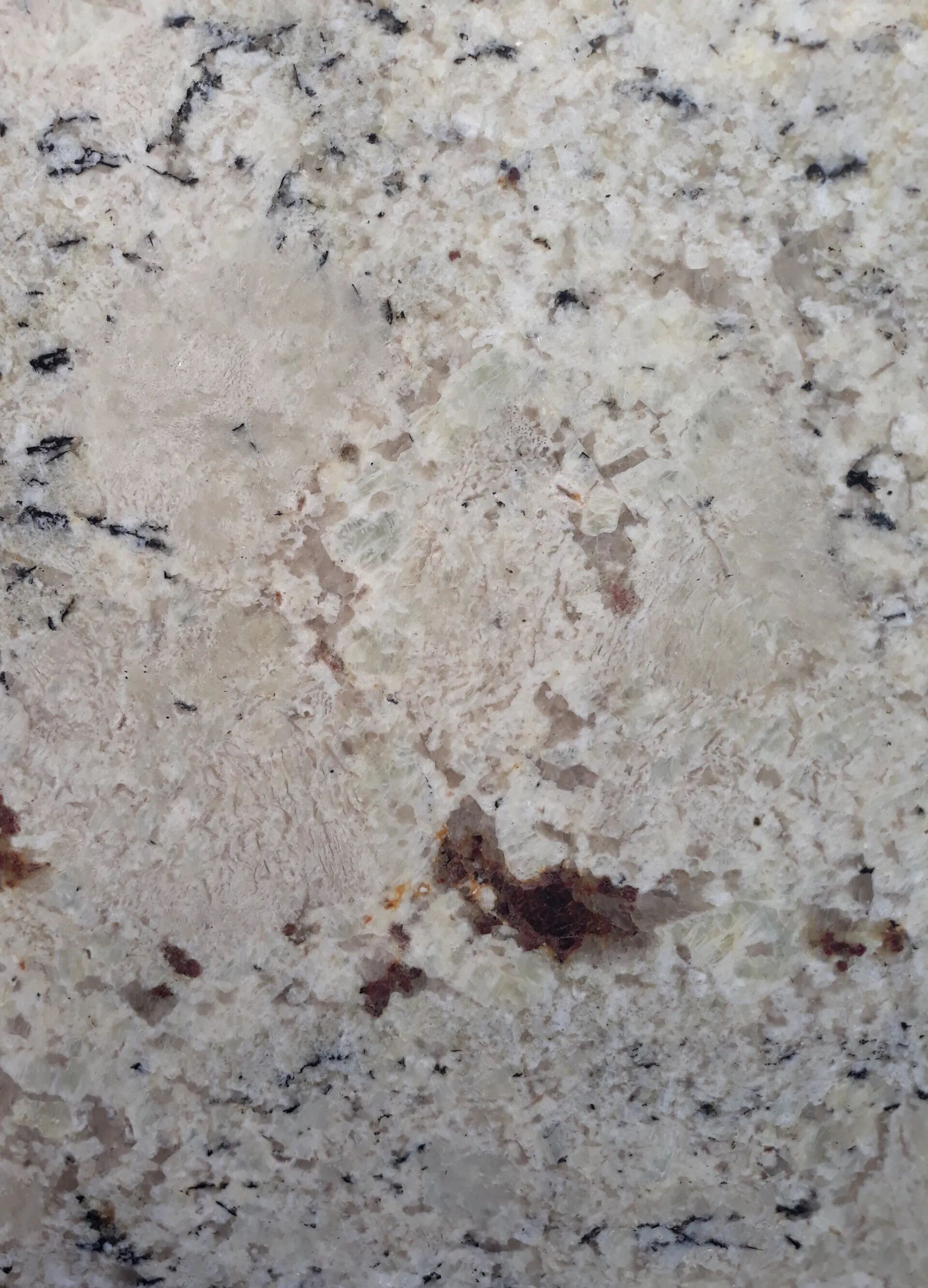 Close-up of a speckled gray granite surface with a small brown stain.