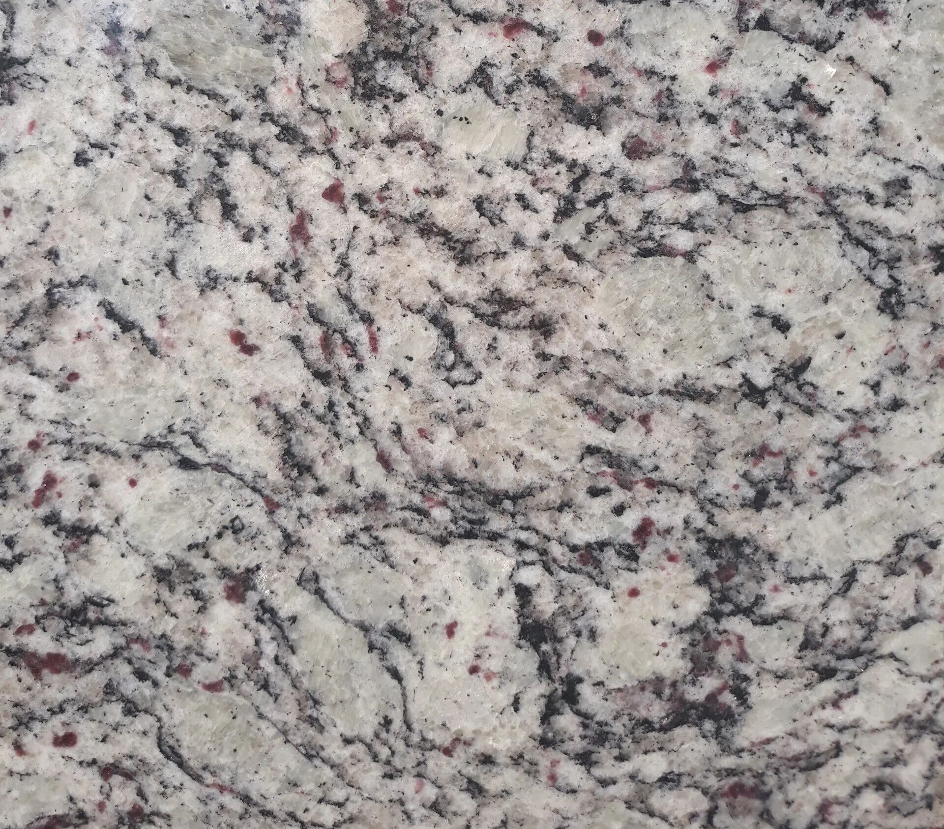 Close-up of a light gray granite surface with black, white, and pink speckles and veins