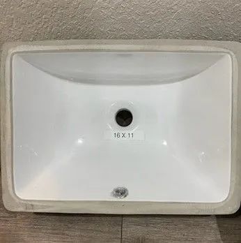 White bathroom sink with a single center drain hole and a small black mark above it.