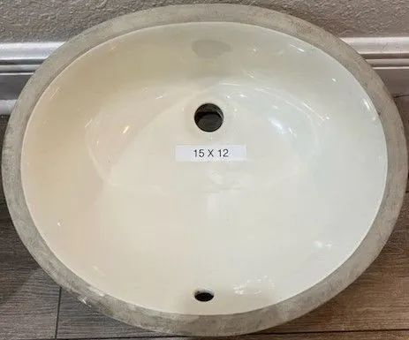 Oval white bathroom sink with gray stone rim and two drain openings