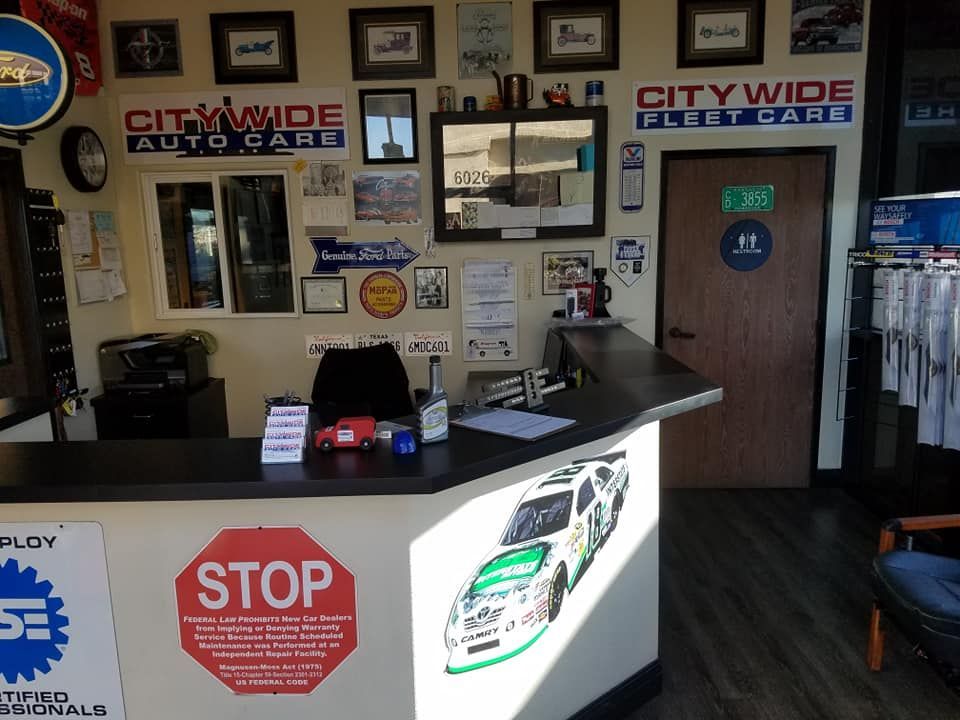 Reception area of a car repair shop with a front desk, logos, and a NASCAR car decal.