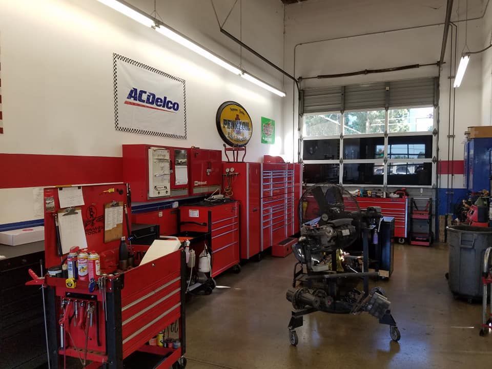 A mechanic's workshop with red tool cabinets, AC Delco banner, and a partially disassembled engine.