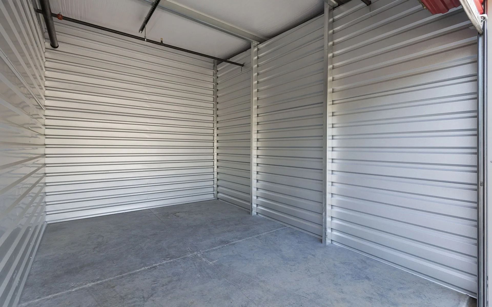 Empty indoor storage unit with corrugated metal walls and concrete floor