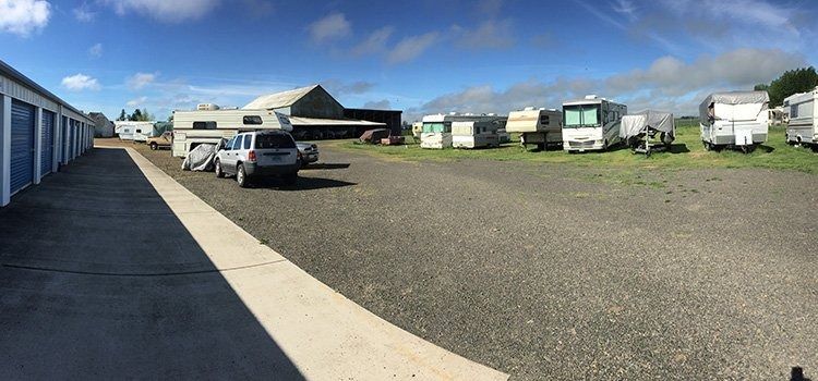 RV campground with parked motorhomes, a gravel lot, and blue sky