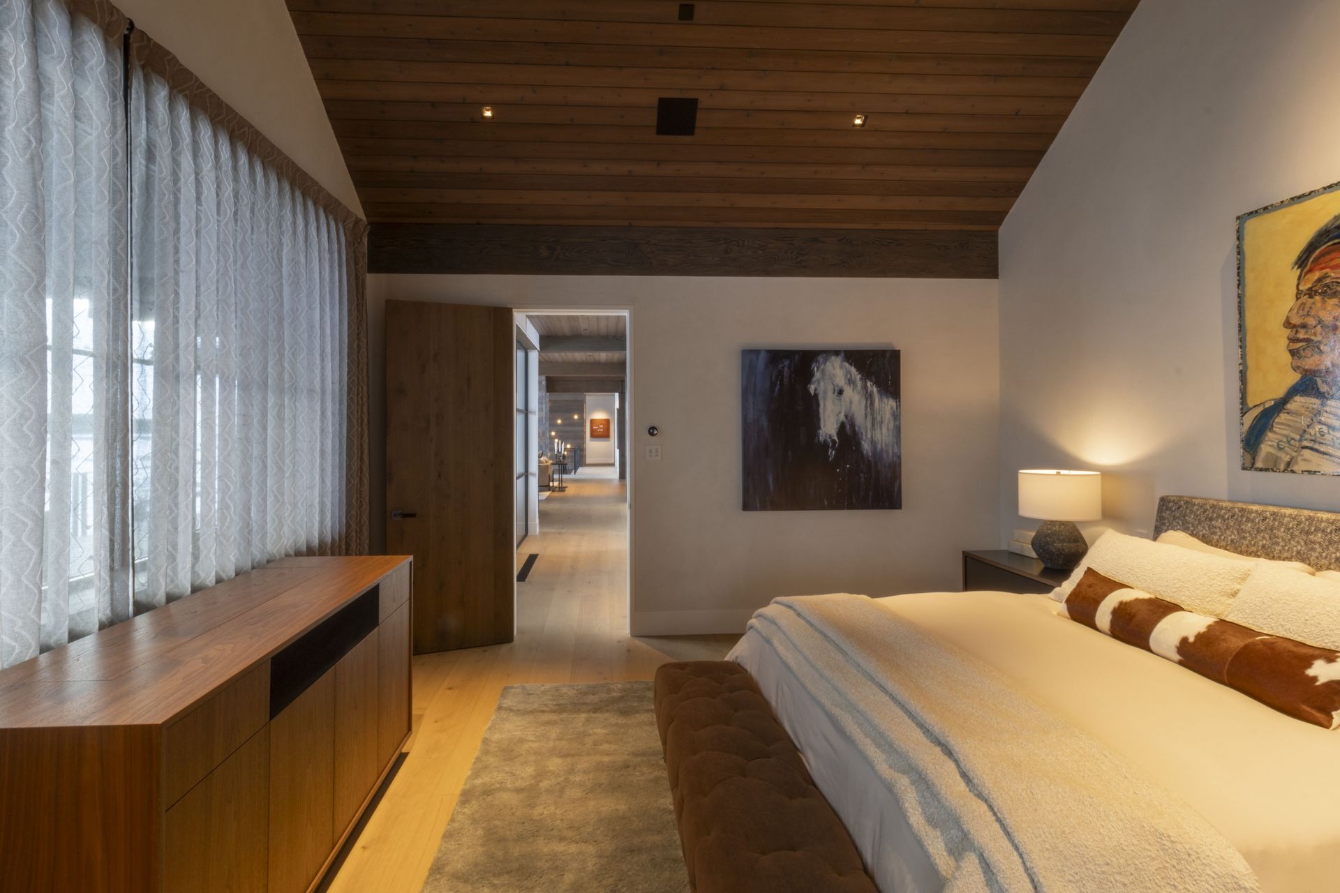 A bedroom with a large bed and a painting on the wall