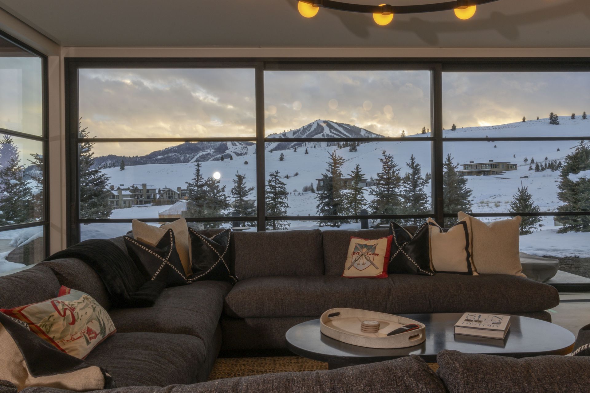 A living room with a large sectional couch and a view of a snowy mountain