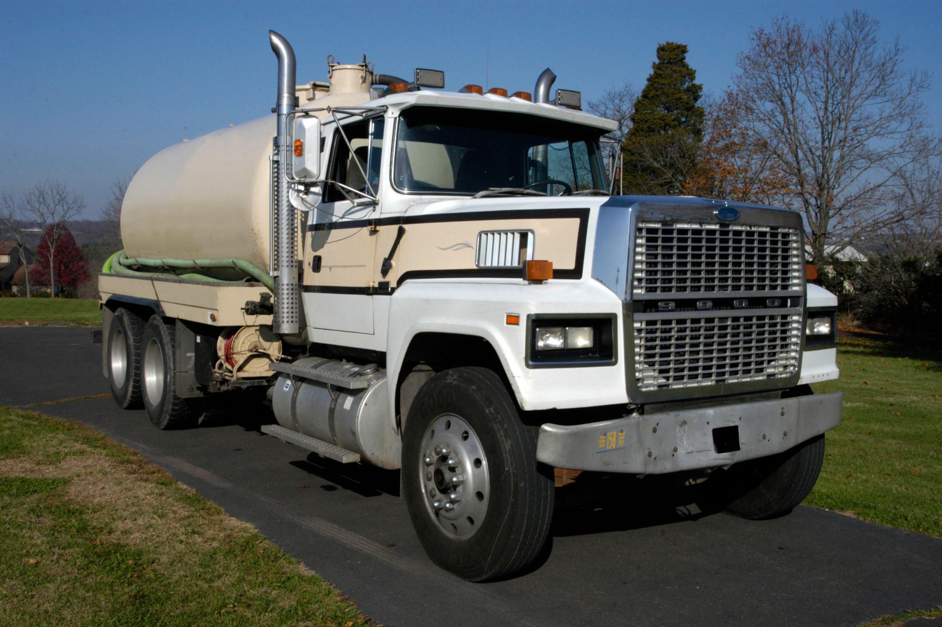 White and tan tanker truck parked on a driveway.