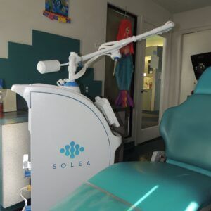 Solea dental laser unit beside a teal treatment chair in a clinic room
