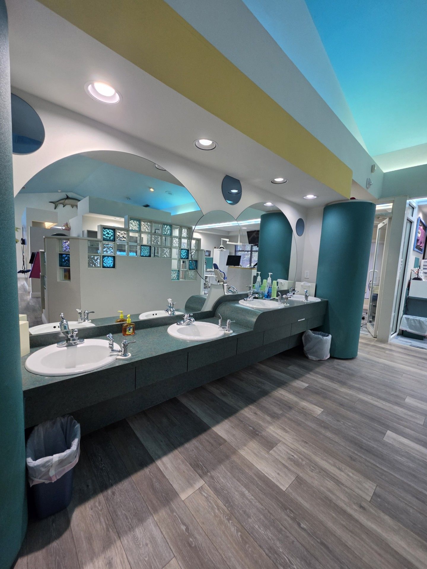 Modern bathroom with double sinks, dark vanity, arched mirrors, and blue walls