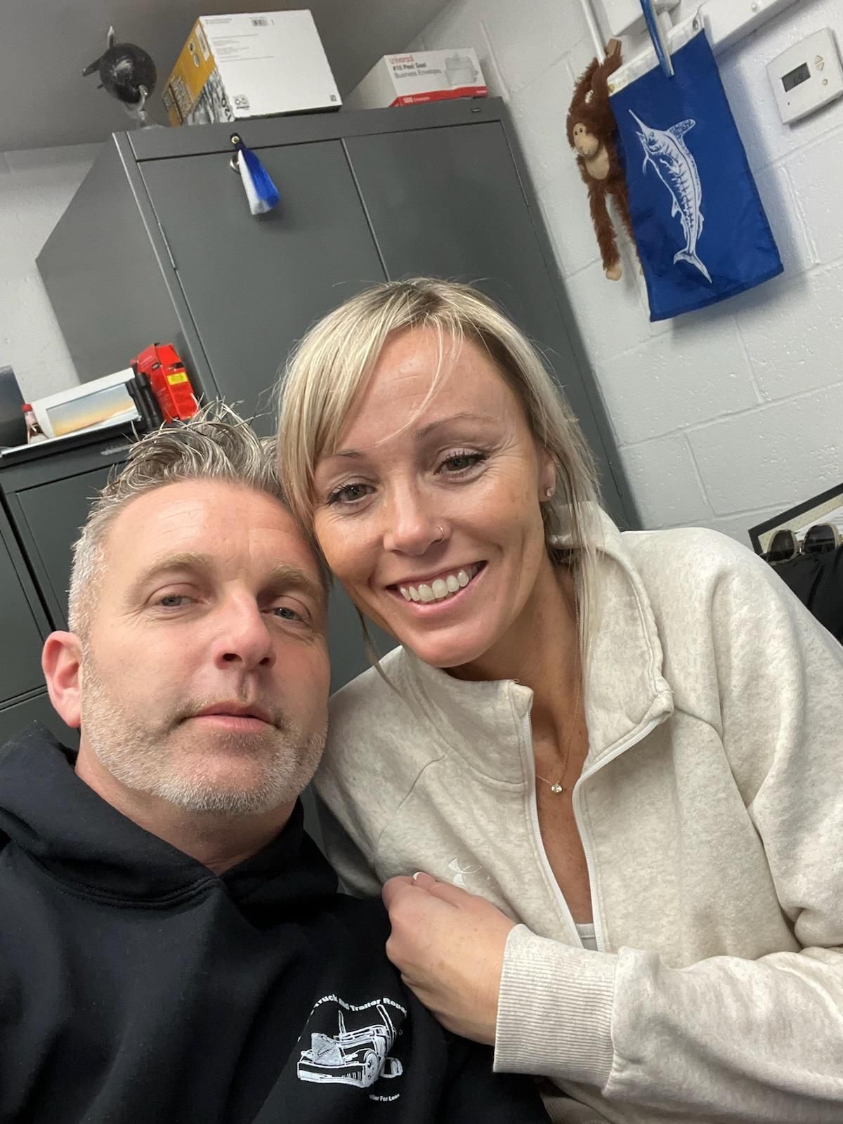A man and a woman are posing for a picture in a room.