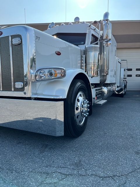 A white semi truck is parked in front of a garage door