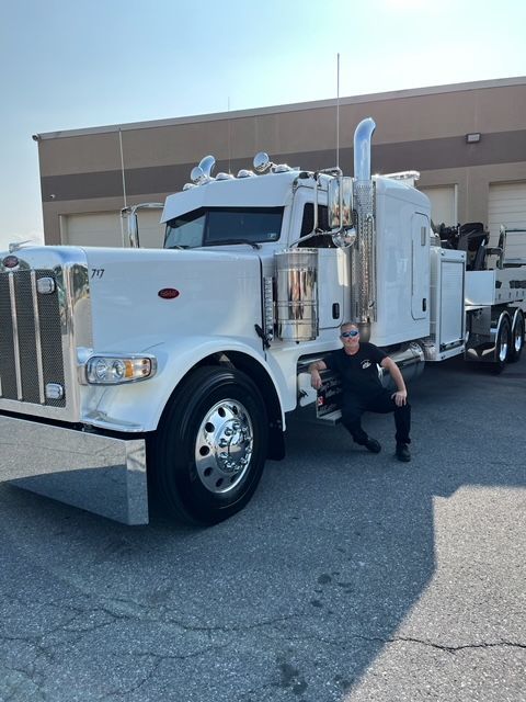 A man is kneeling next to a large white truck
