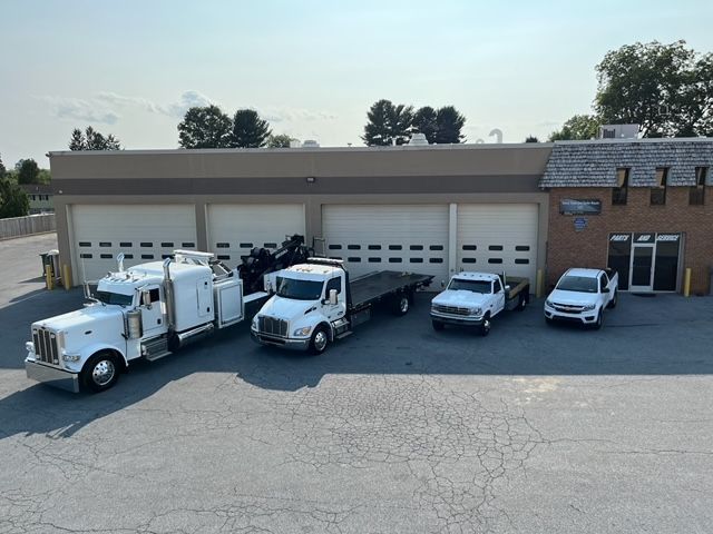 A group of tow trucks are parked in front of a building.