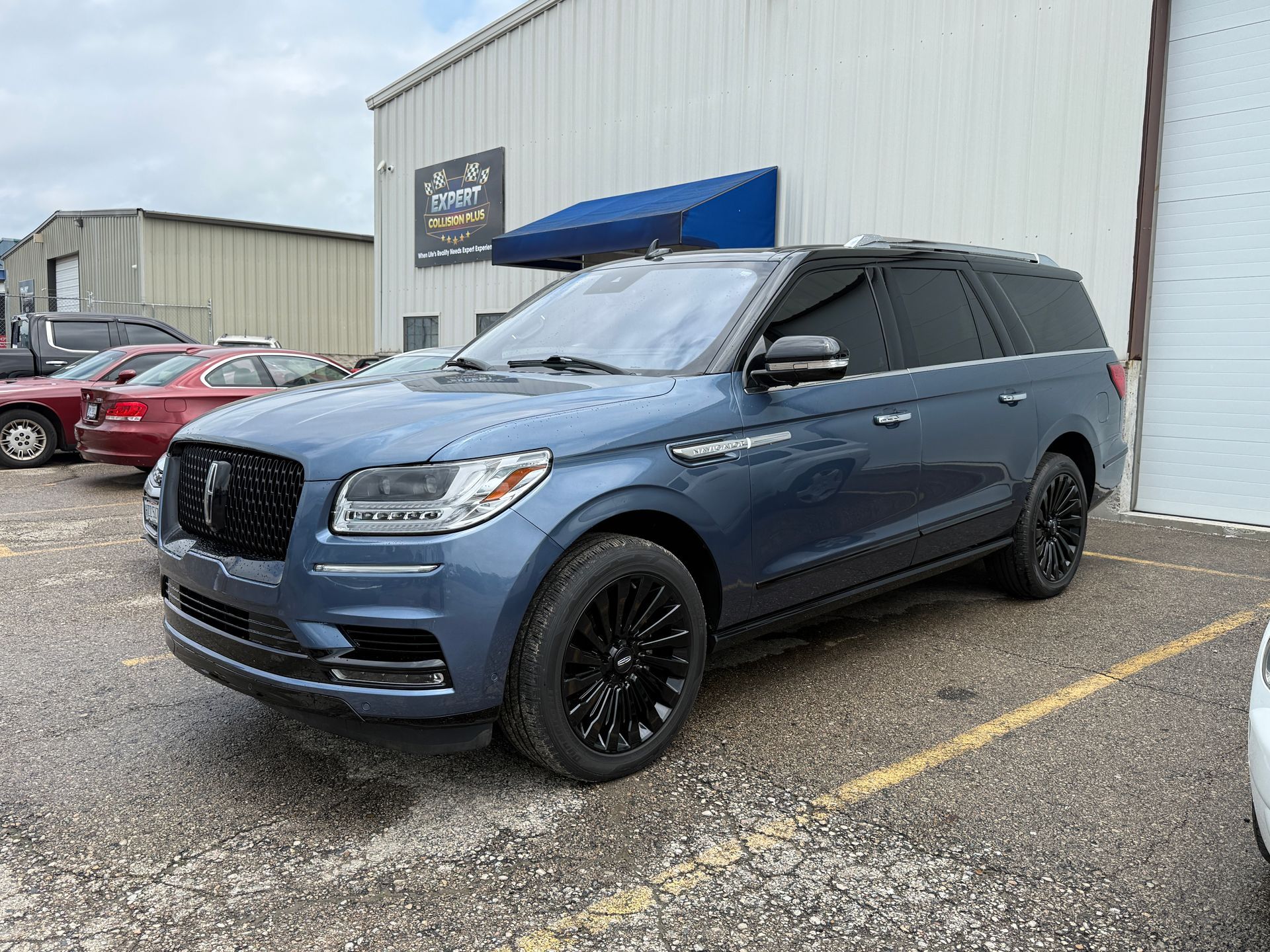 Blue luxury SUV parked outside a building on a wet lot