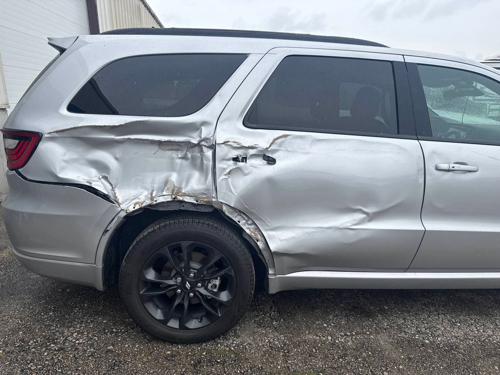 Gray SUV with severe side damage and crumpled rear door and quarter panel after a crash