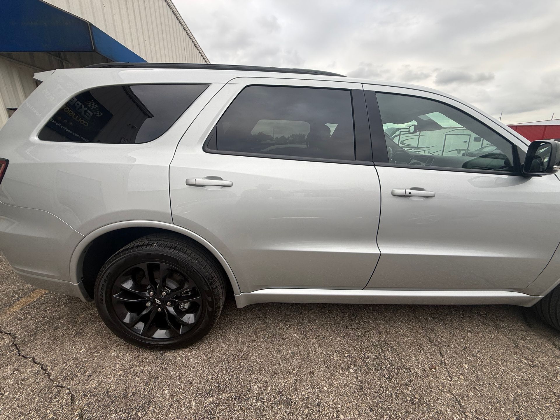 Silver SUV parked beside a building, shown in side view on gravel.