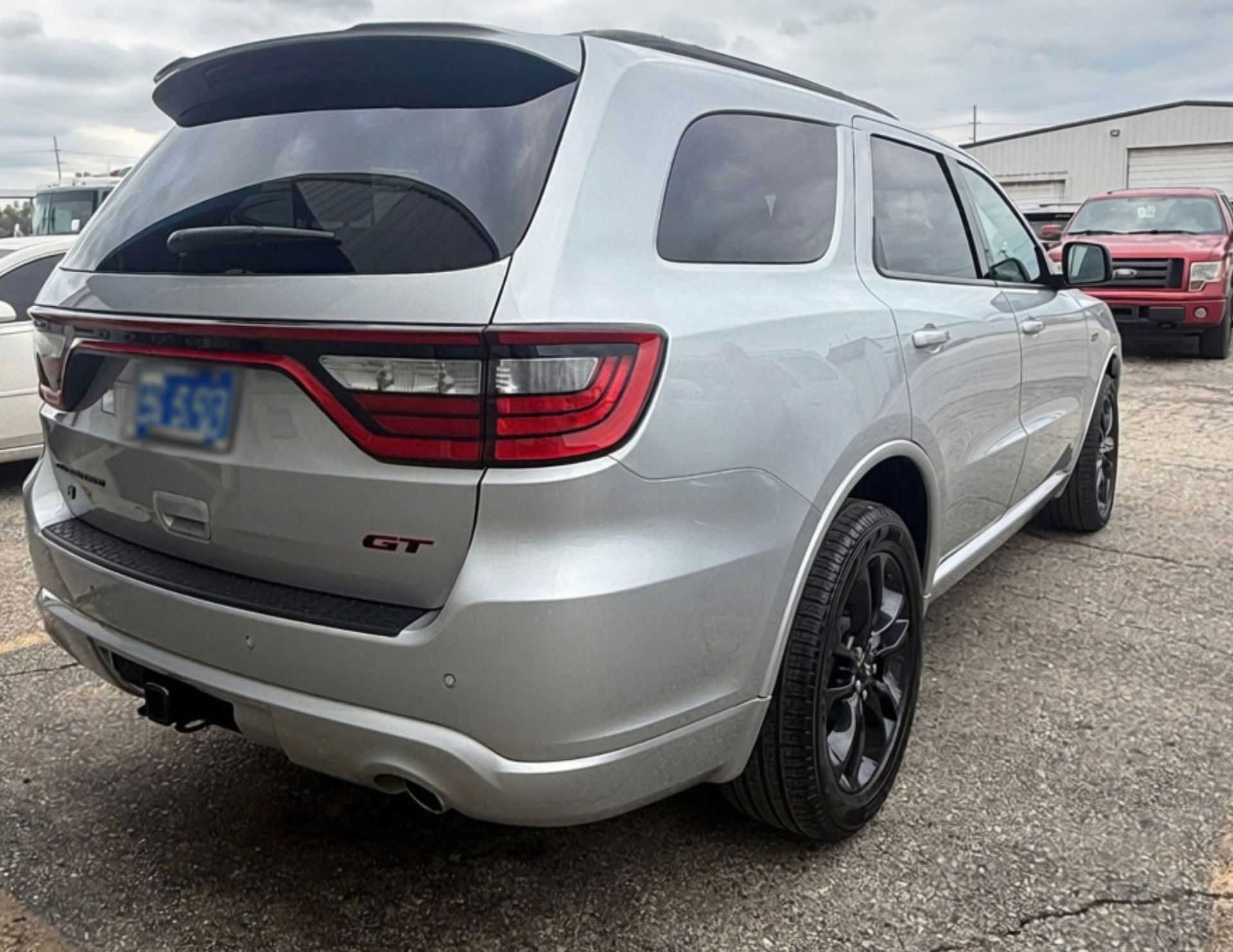 Silver SUV parked in a lot, rear three-quarter view with tinted windows and black wheels