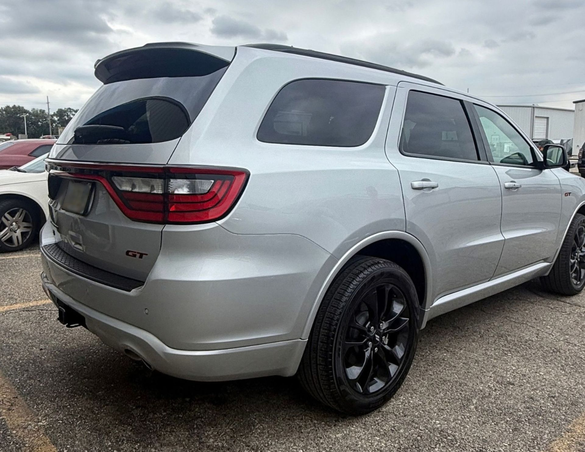 Silver Dodge Durango GT SUV parked on a gravel lot, rear three-quarter view with black wheels