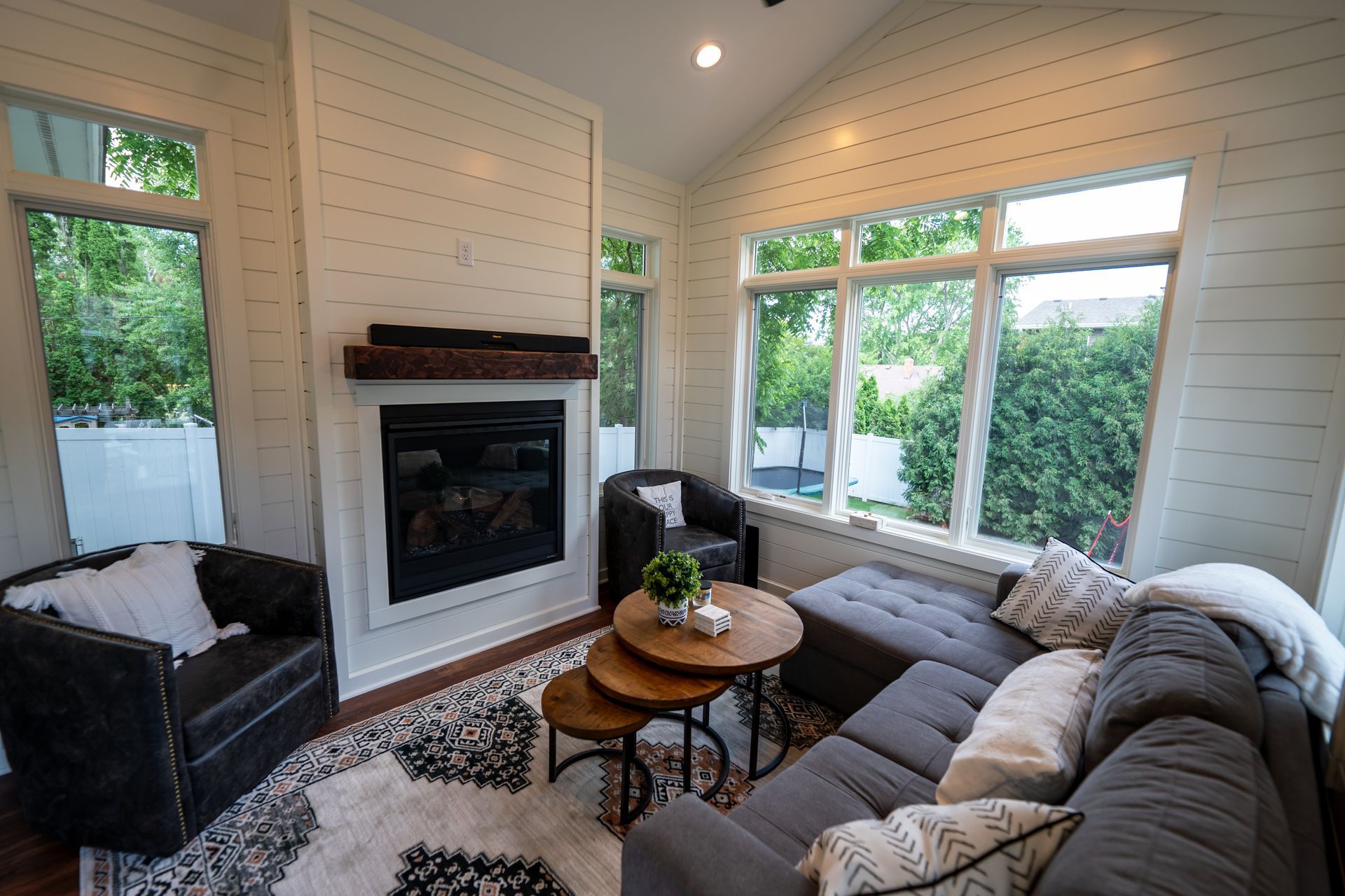 Living room with fireplace, sectional sofa, round coffee tables, and large windows.