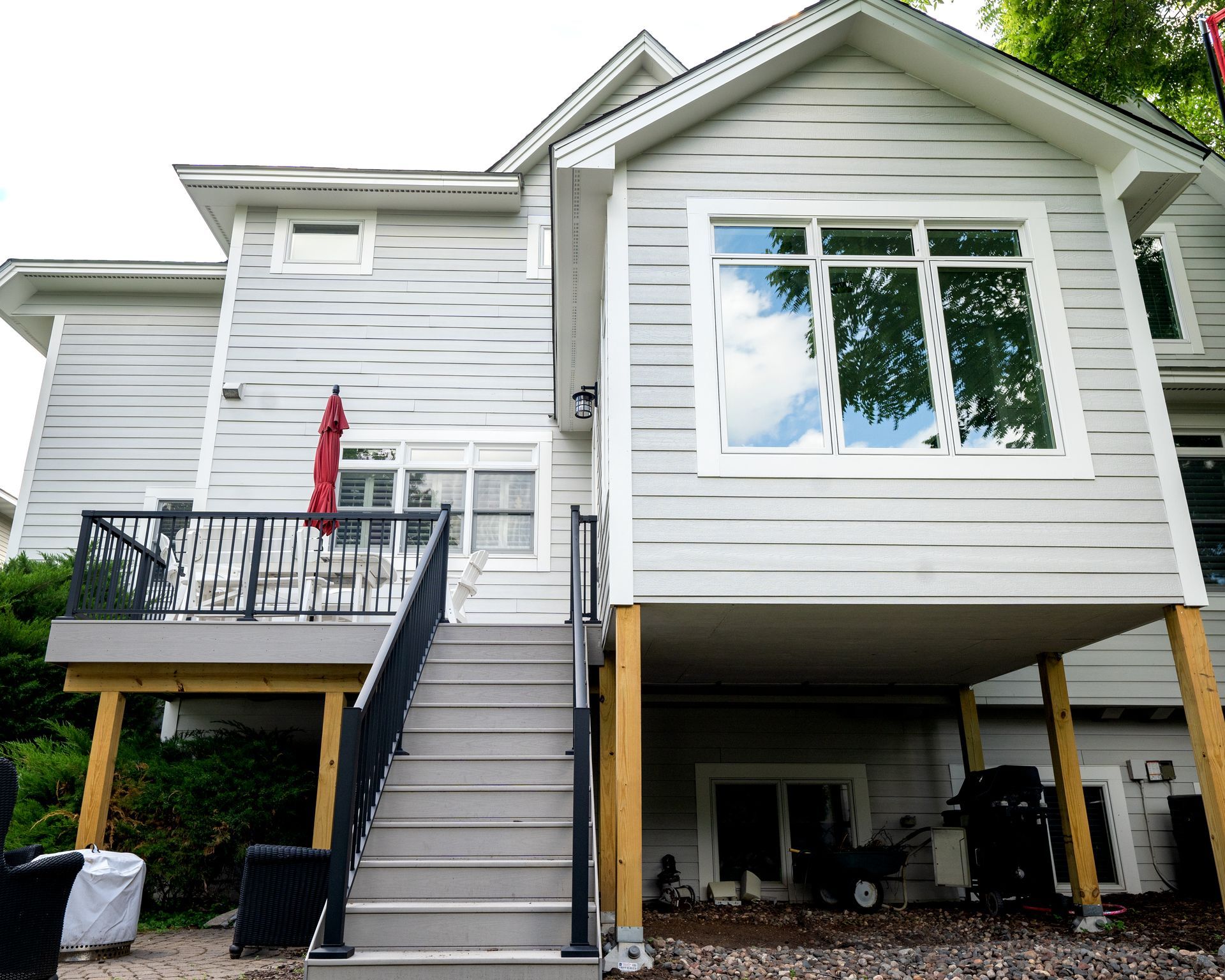 Exterior of a two-story house with a deck, stairs, and light-colored siding.