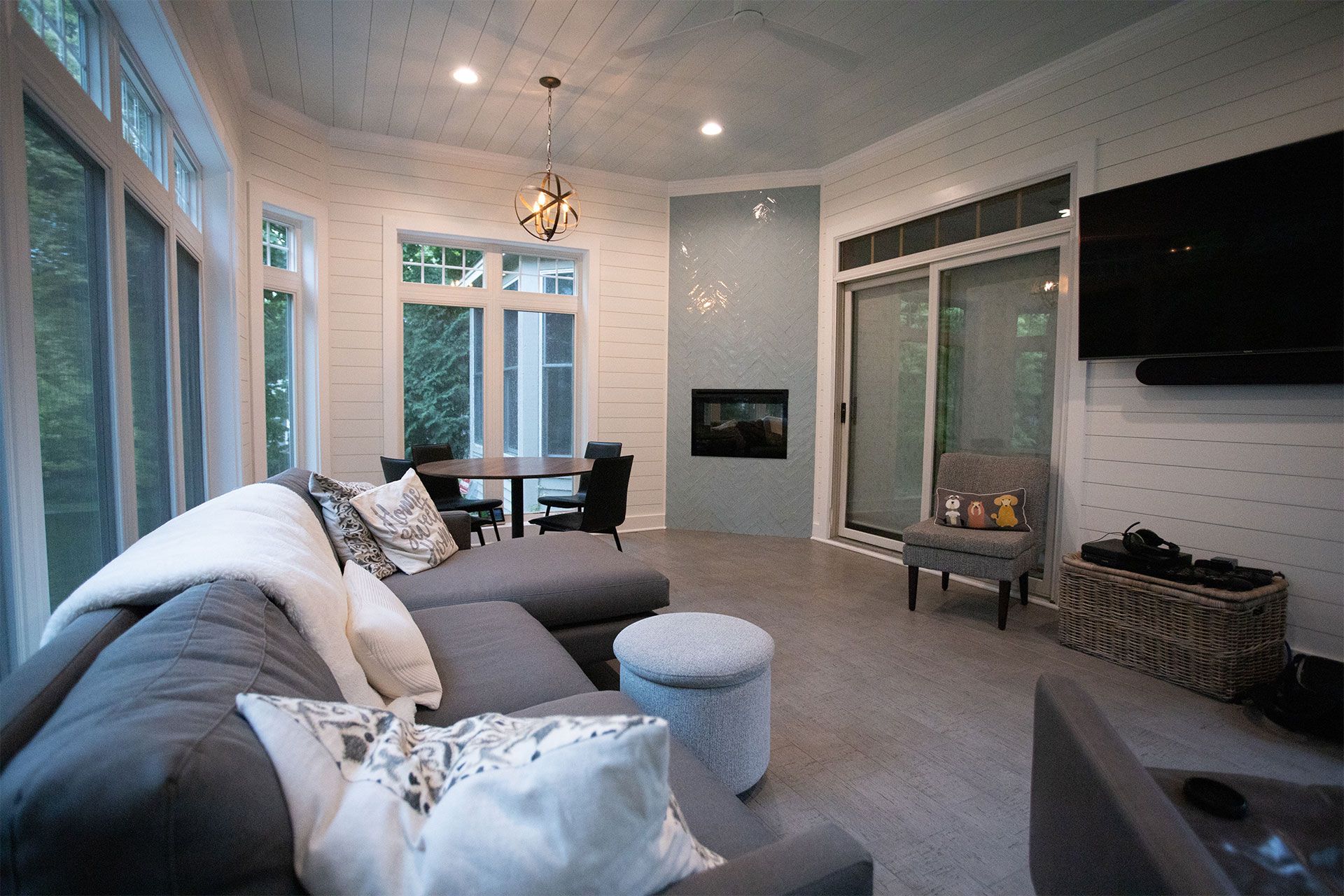 Gray sectional sofa in a sunroom with a fireplace and large windows.