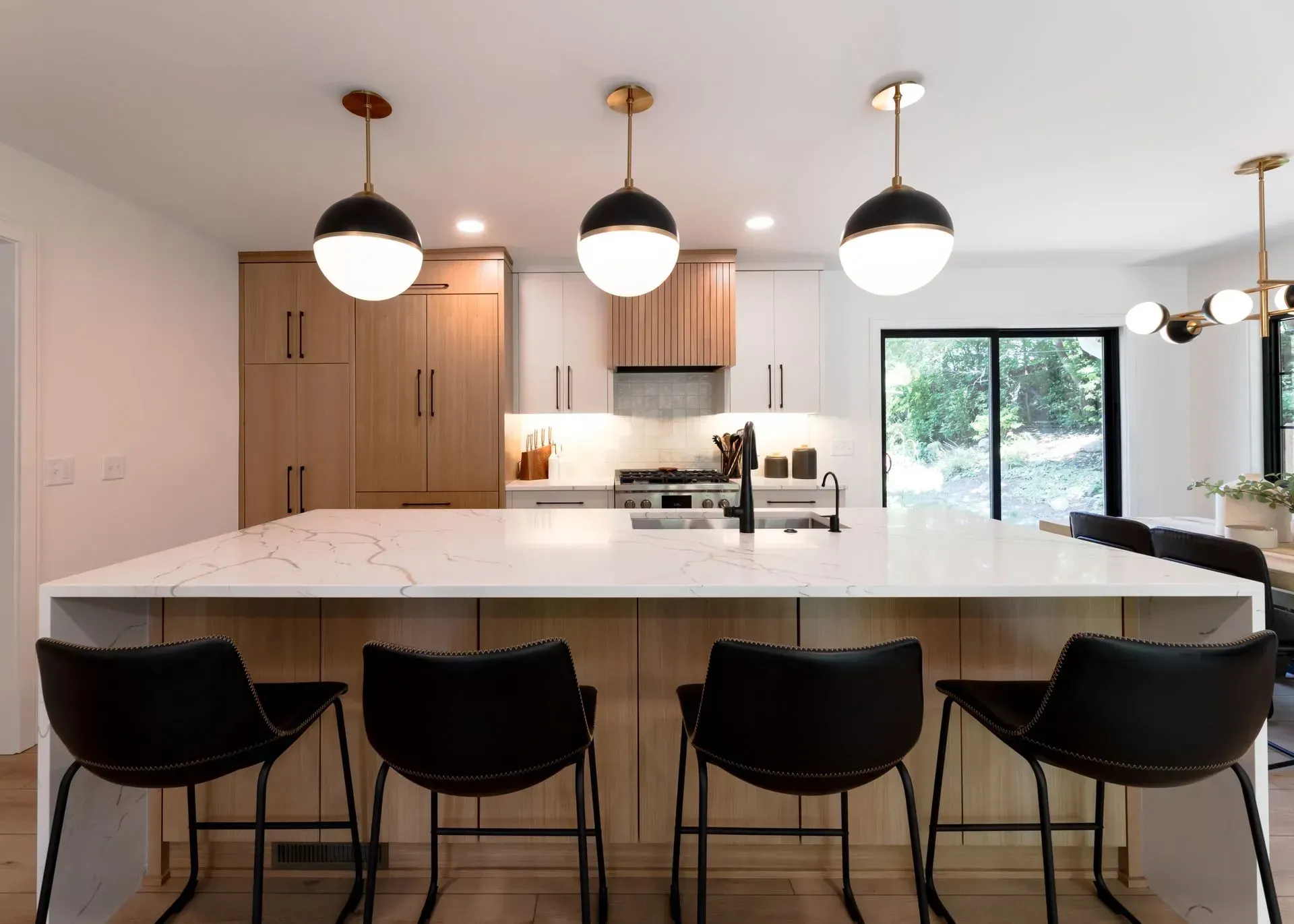 Modern kitchen with island, pendant lights, and black bar stools.