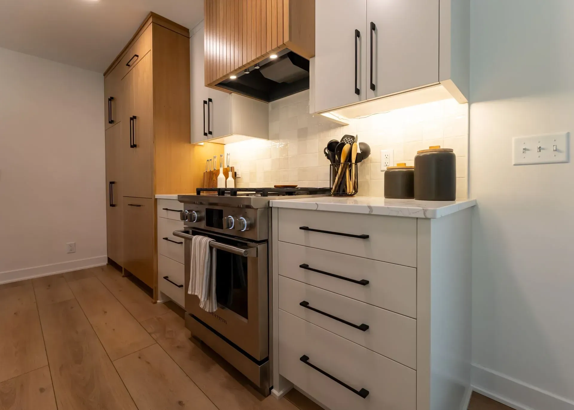 Modern kitchen with stainless steel appliances, white cabinets, and wooden accents.