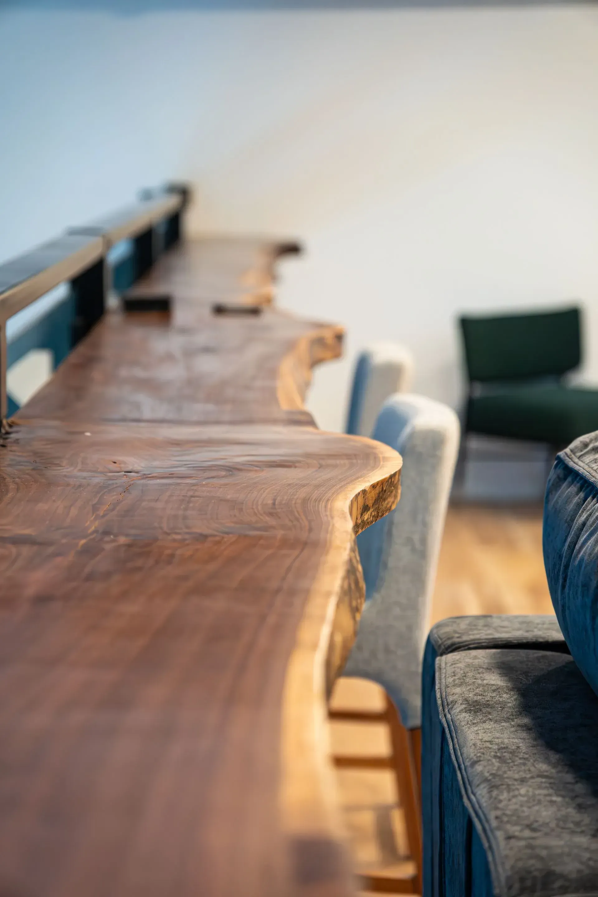 Wooden counter with live edge, light-colored chairs, and a dark green chair in the background.