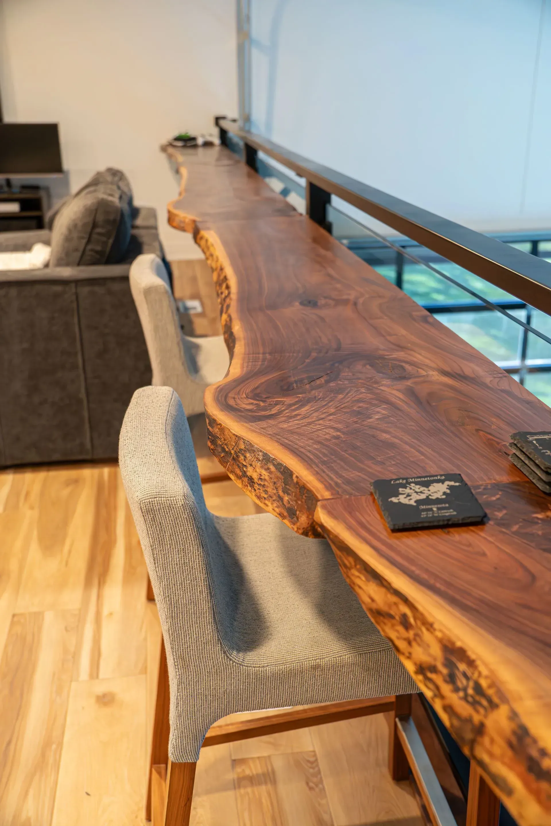 Long wooden bar with natural edge and two bar stools.