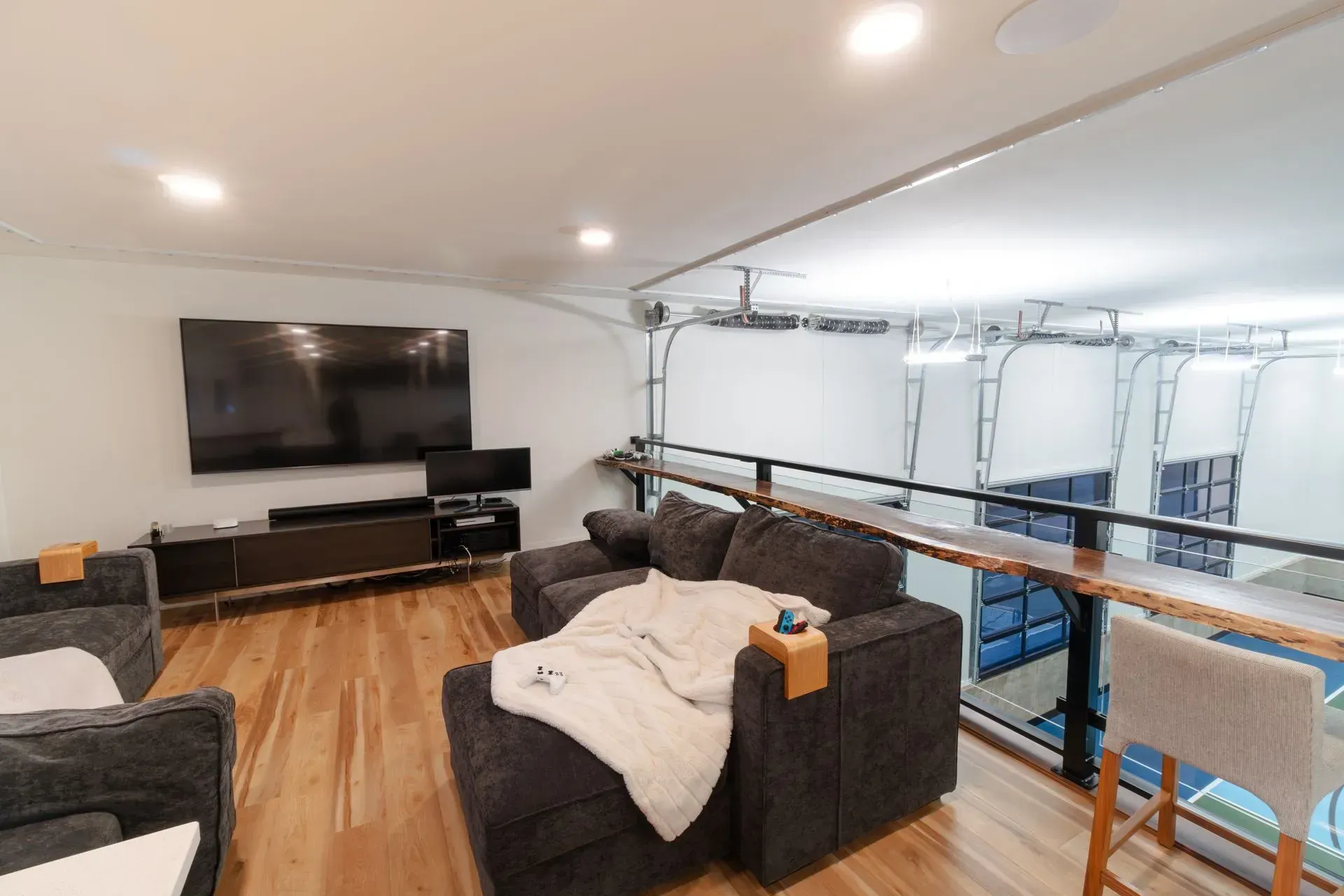 Loft living area with TV, couches, wooden floor, and a bar area with stools.
