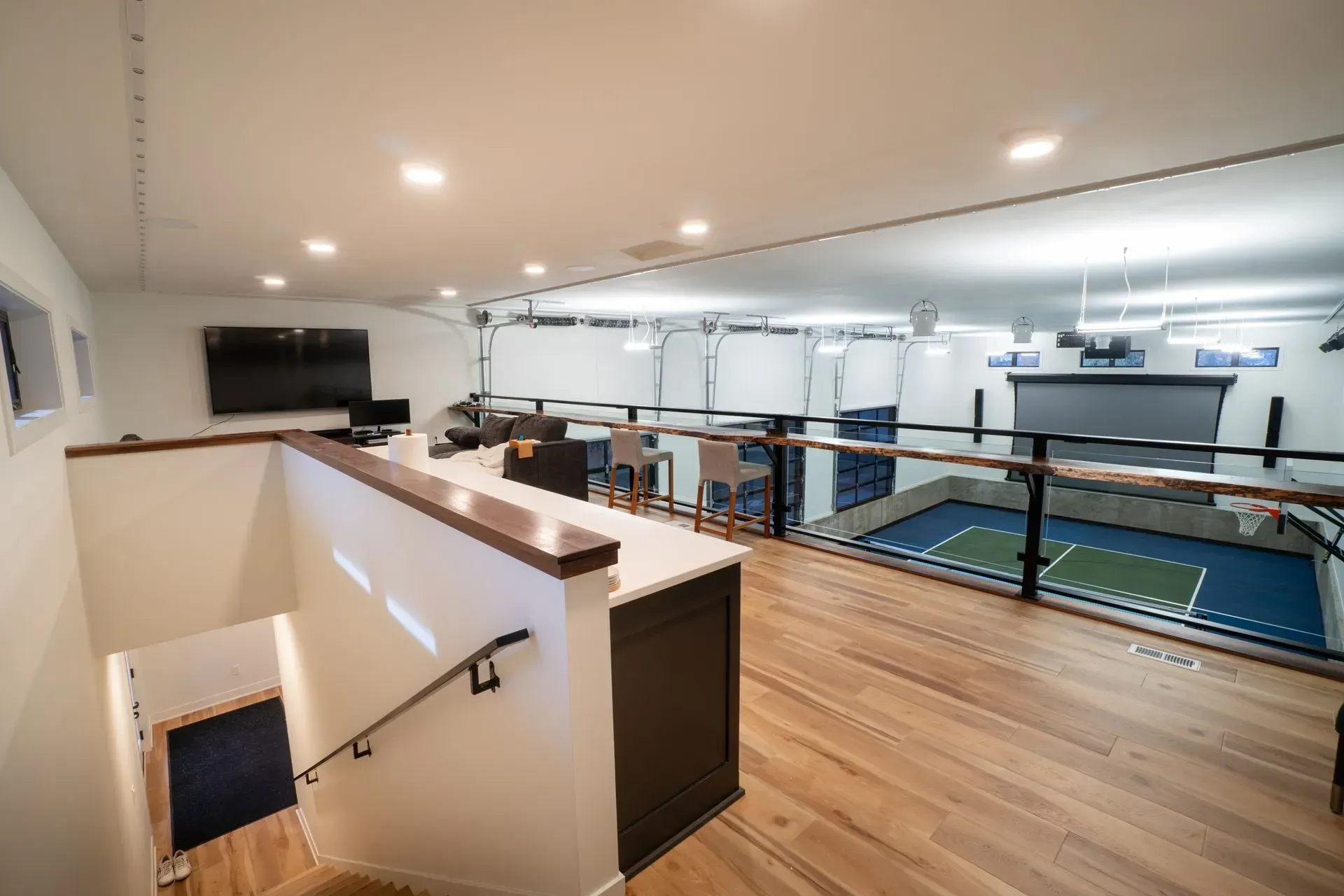 Multi-level sports simulation space with indoor court, TV, and bar area.