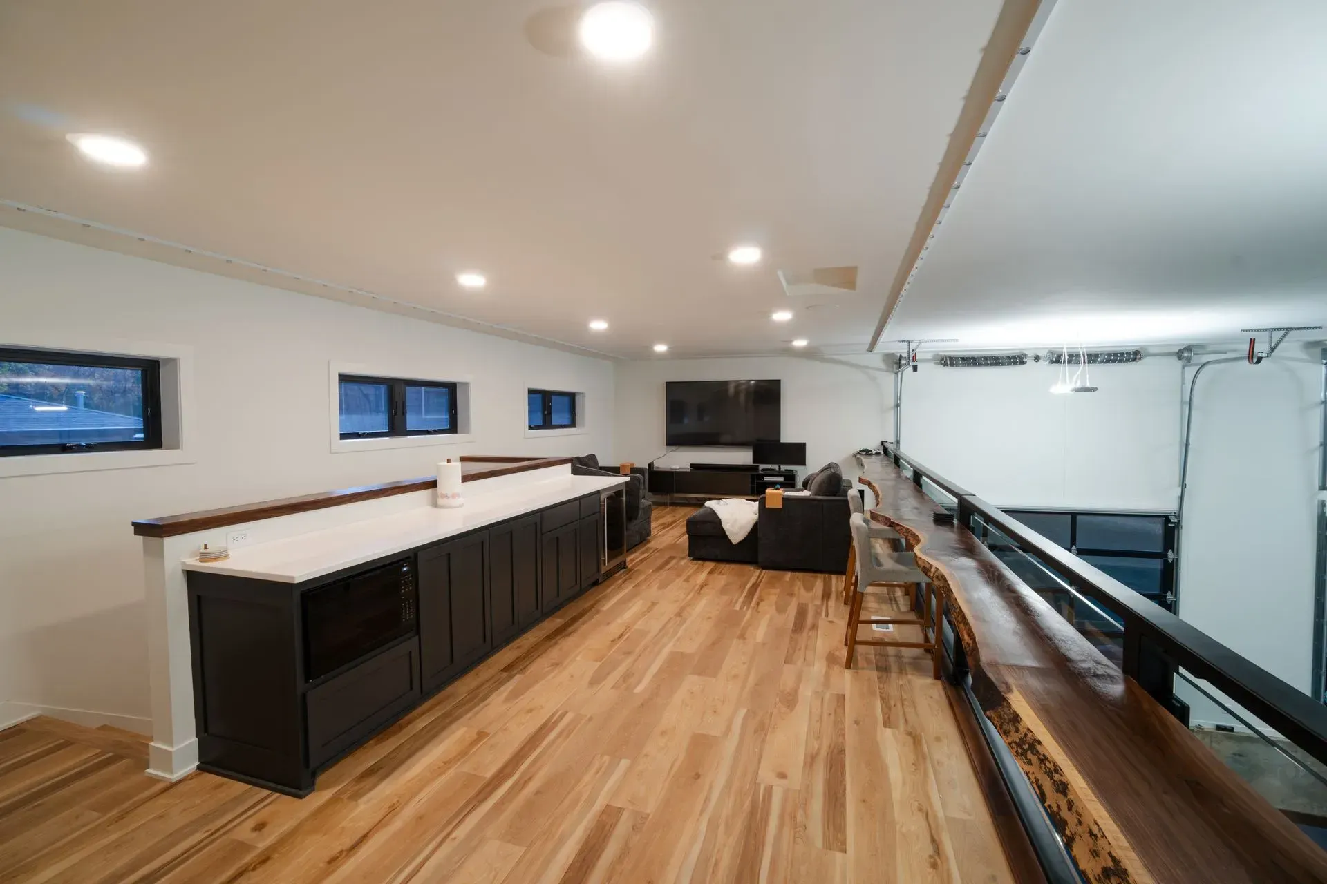 A modern loft with a kitchen island and seating area. Wooden floors and white walls.