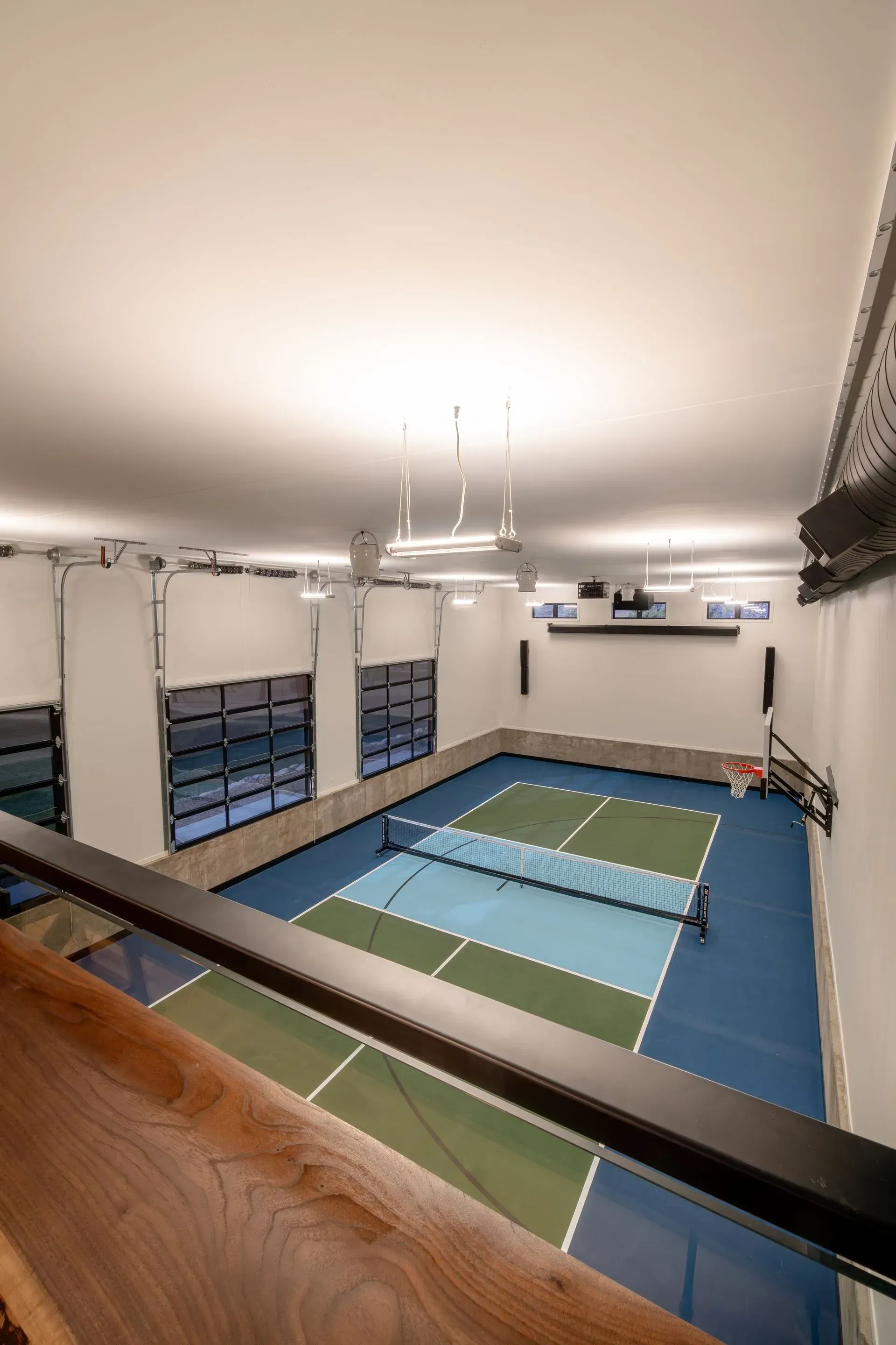 Indoor pickleball court with blue and green playing surfaces, viewed from a high angle.