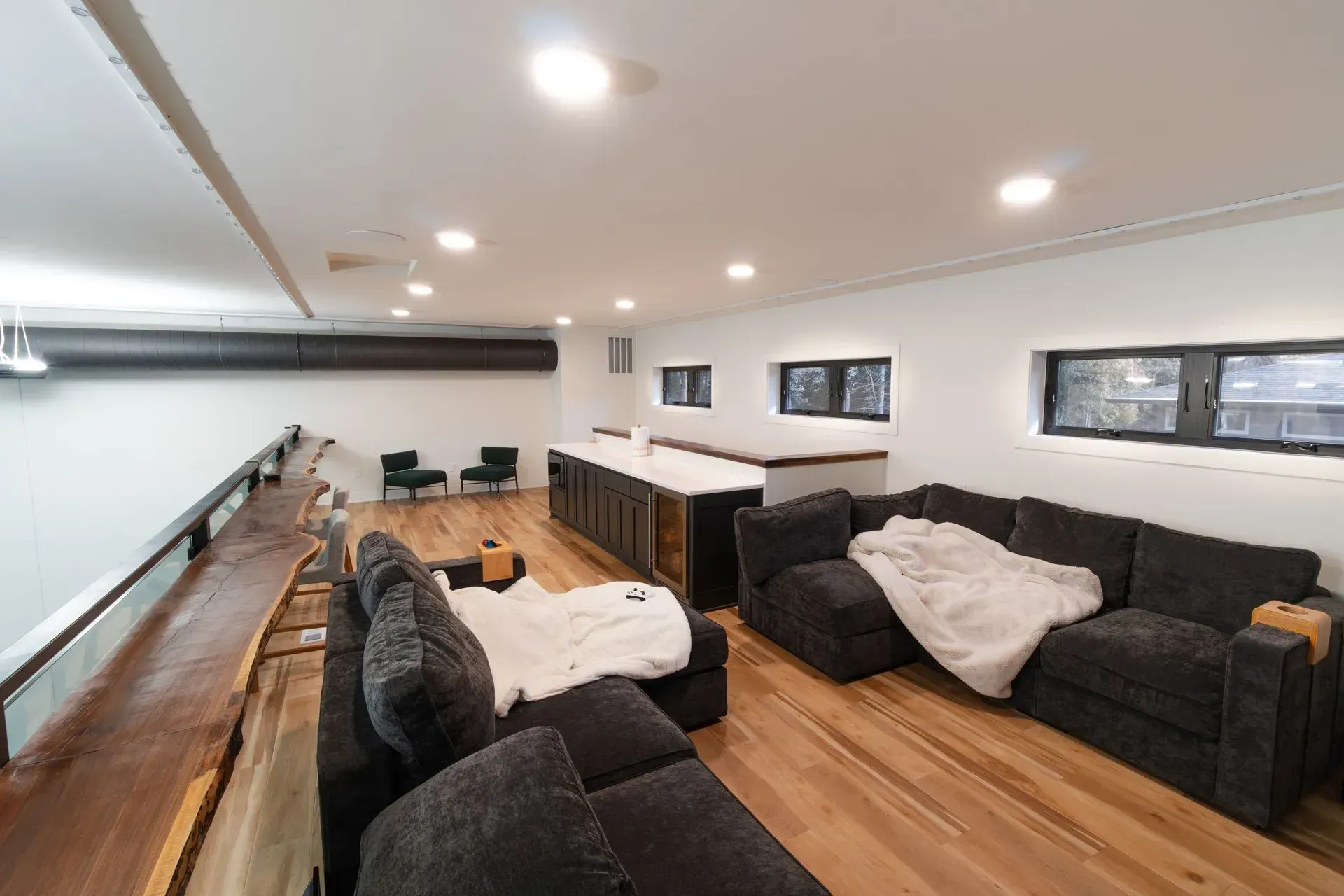 Spacious open-concept living area with hardwood floors, a large gray sectional sofa, and a kitchen island.