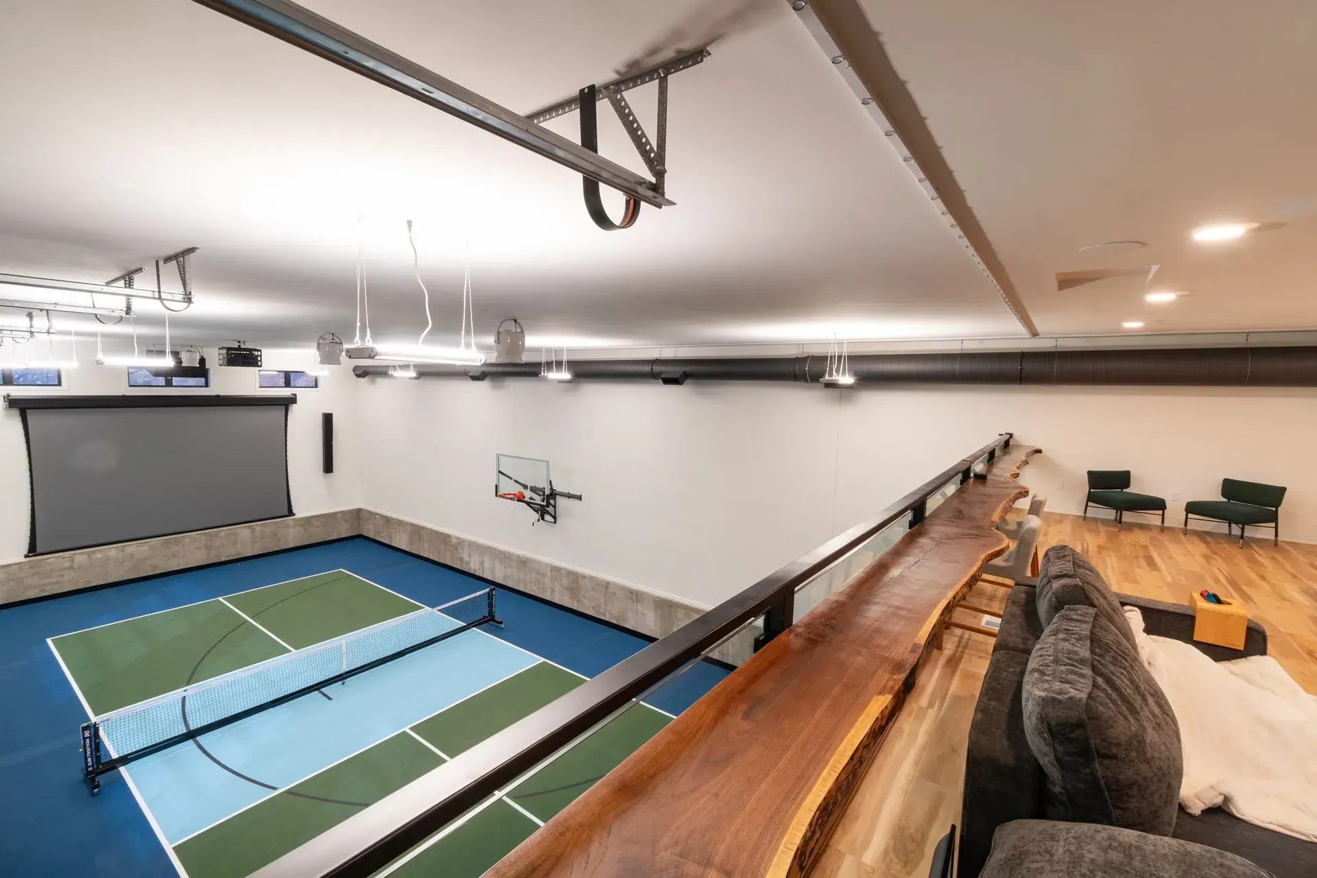 Indoor recreational space with a pickleball court and viewing area.