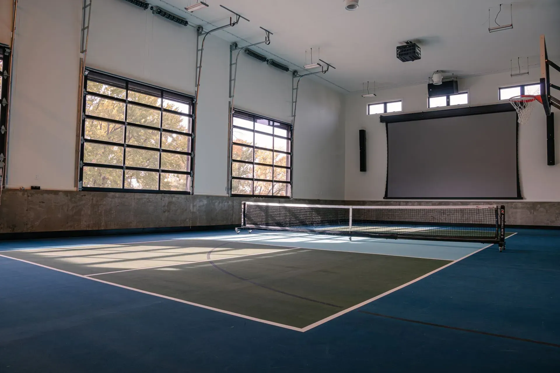 Indoor multi-purpose room with a table tennis setup and projection screen.