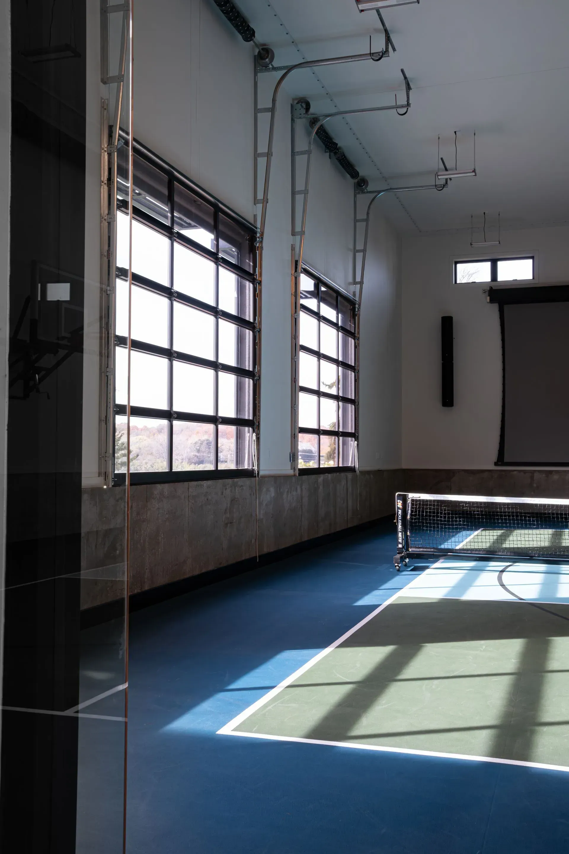 Indoor space with blue floor and windows, sunlight casts shadows.
