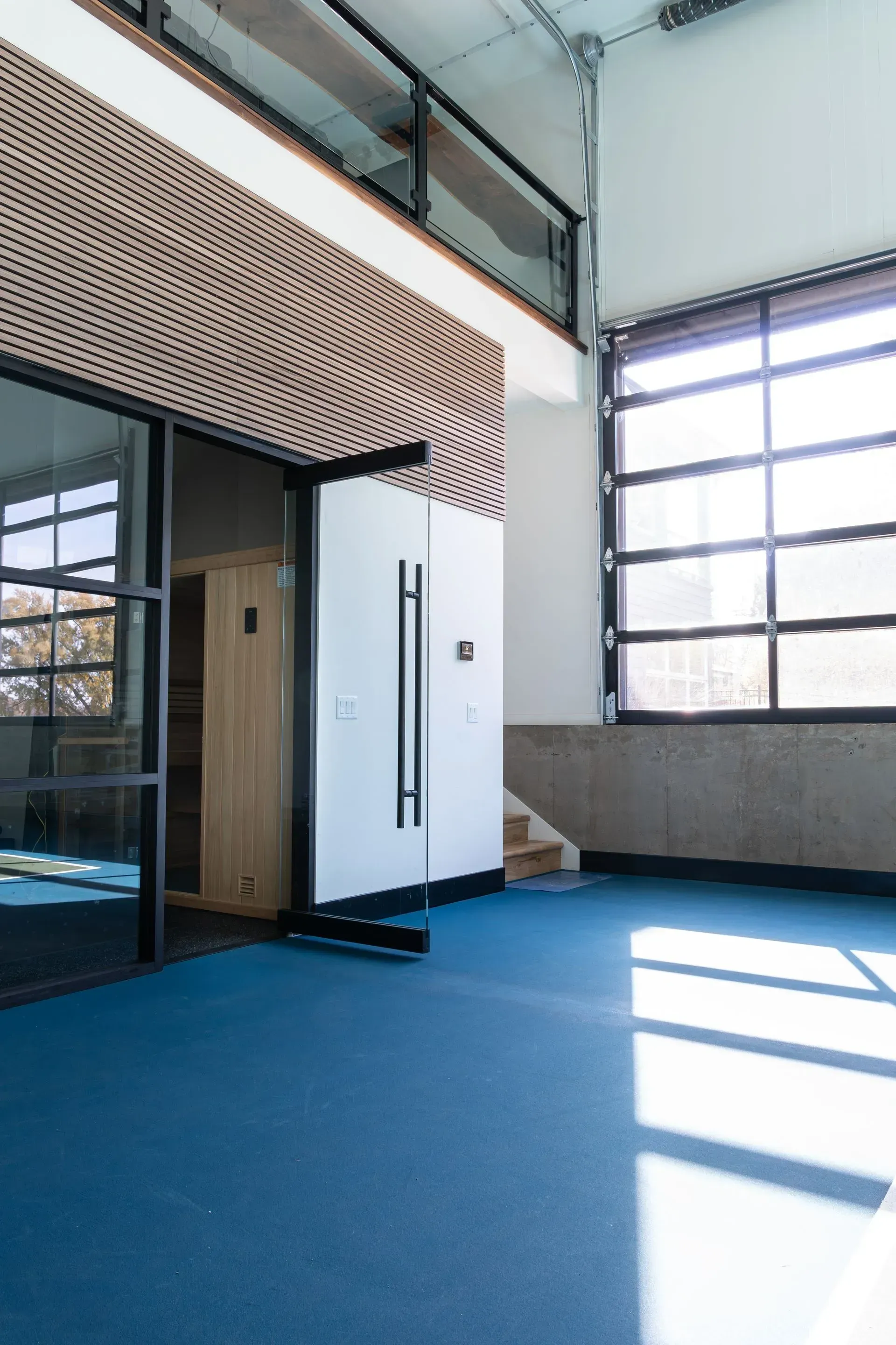 Blue floor interior with glass doors, a white door, and a large window.