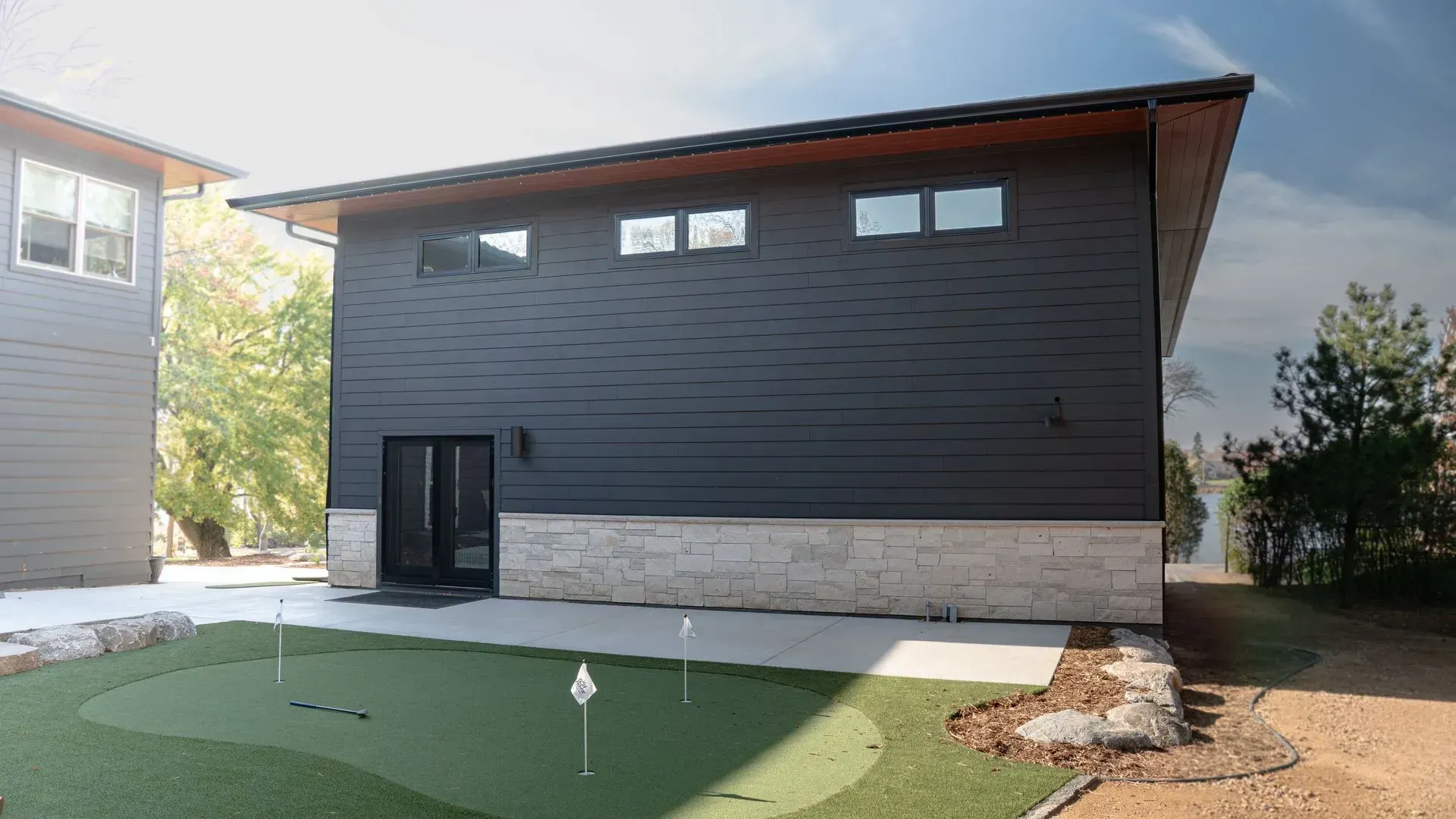 Dark gray building with stone base, putting green, and small windows.