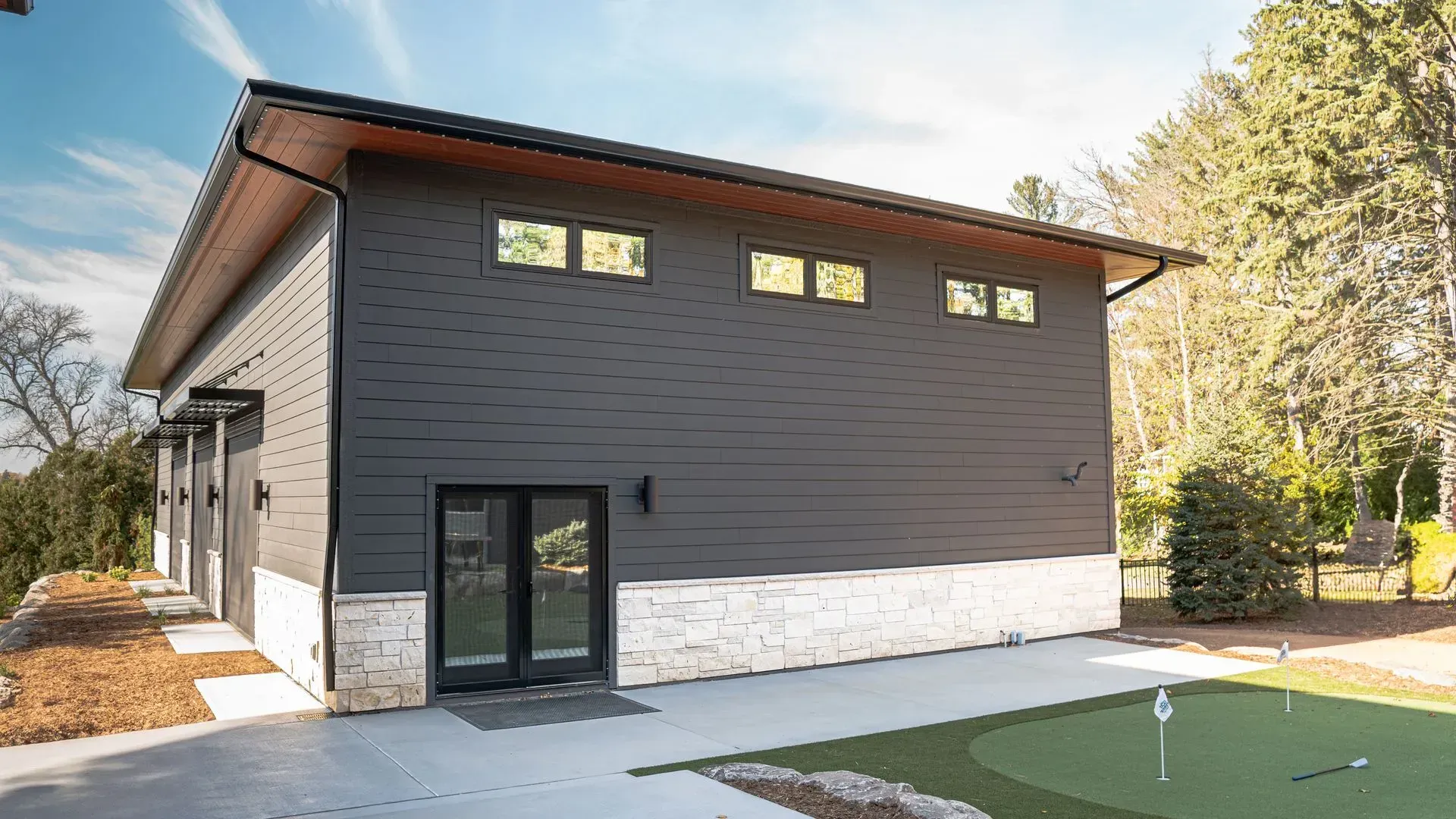 Modern dark gray building with a golf green in the foreground.
