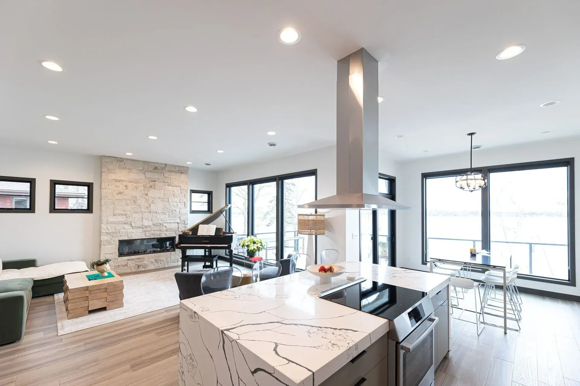 Modern open-plan kitchen and living area with a piano, fireplace, and island.