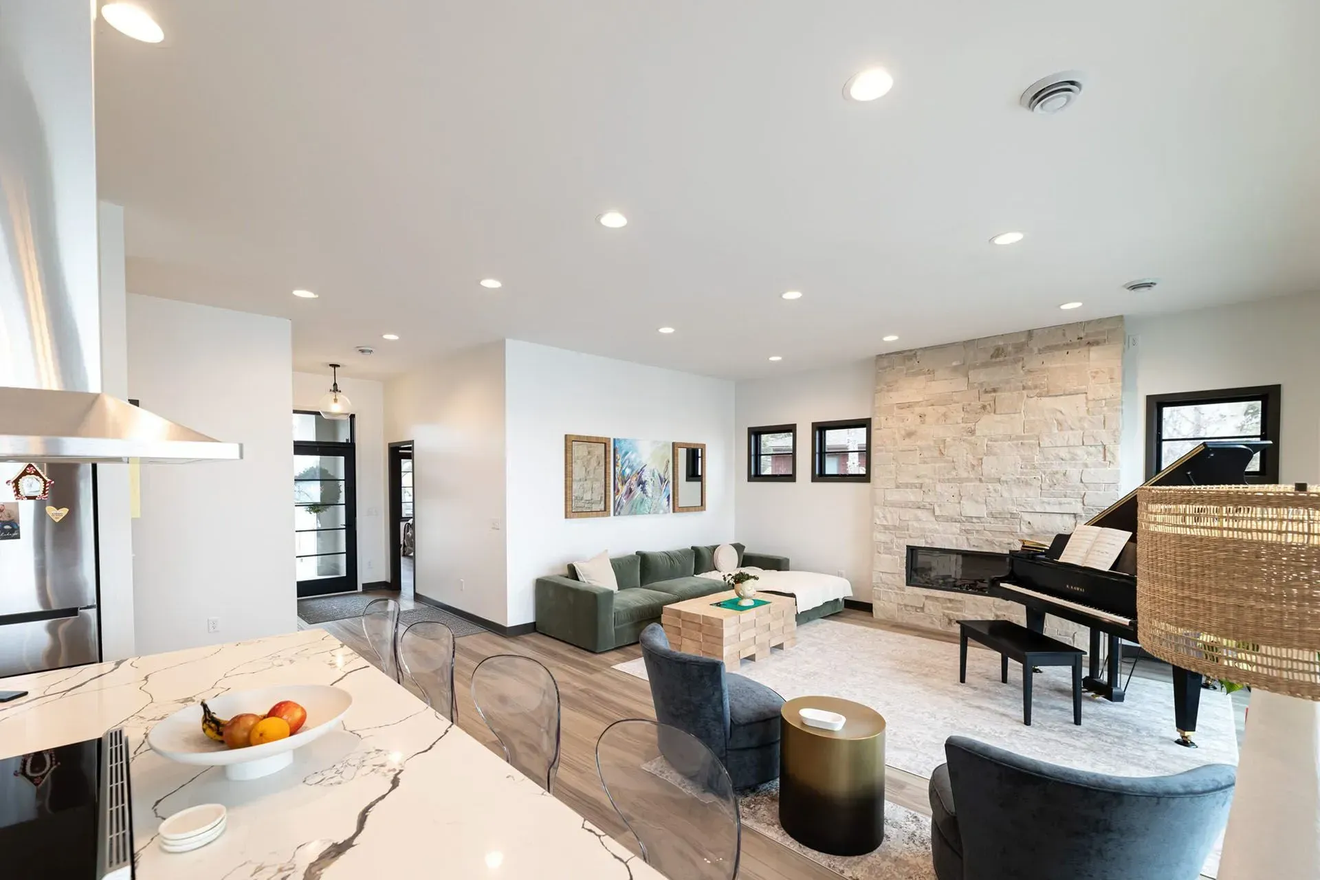 Spacious living room with piano, fireplace, and modern decor. Bright, airy space with neutral tones.