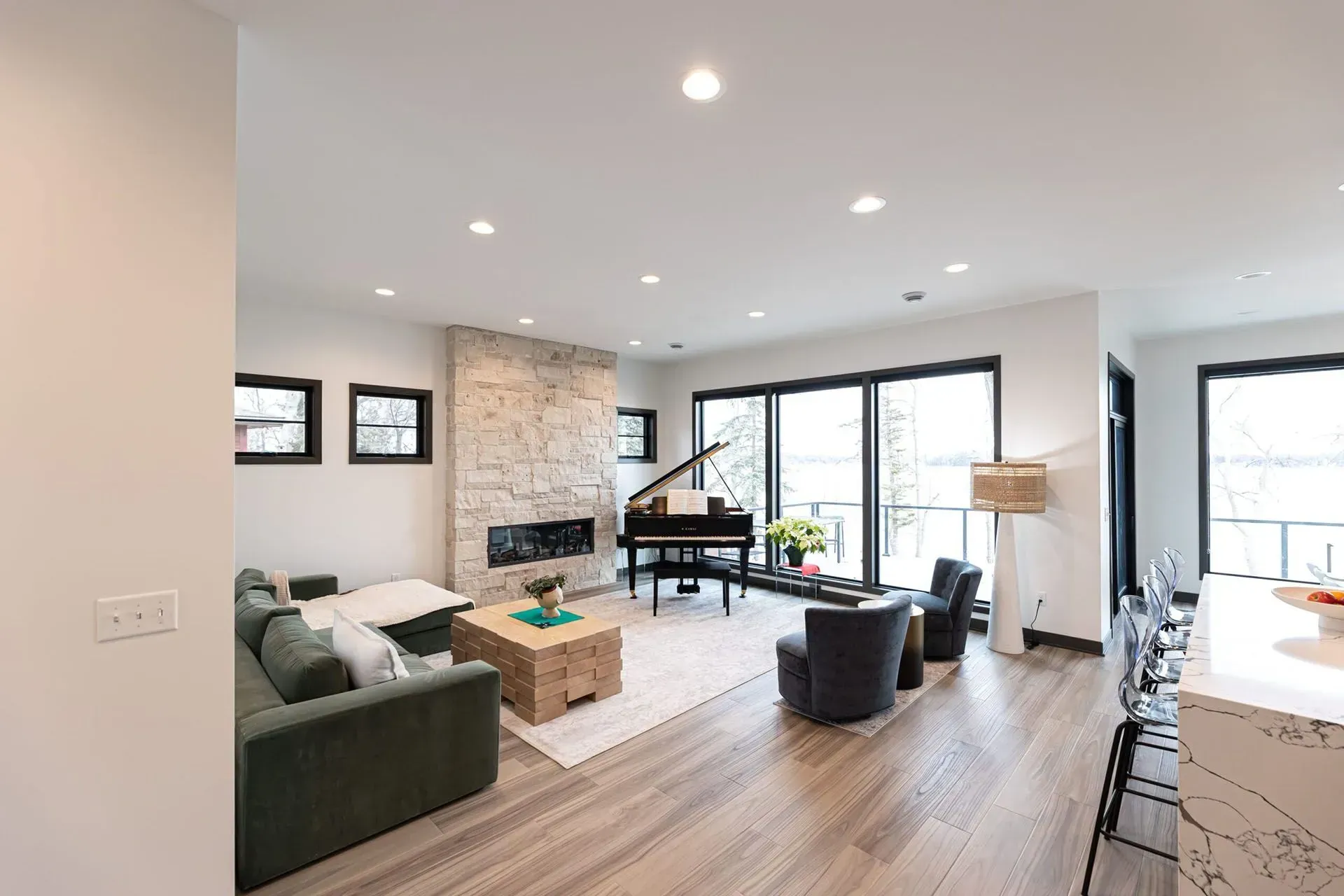 Modern living room with fireplace, grand piano, and large windows.